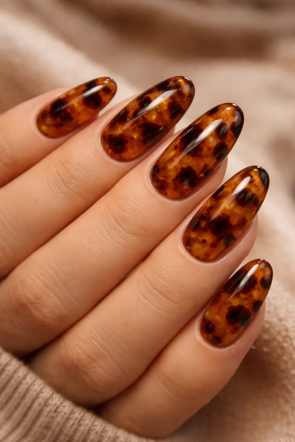 Close-up of tortoiseshell nails with amber-brown layered pattern and 3D jelly finish