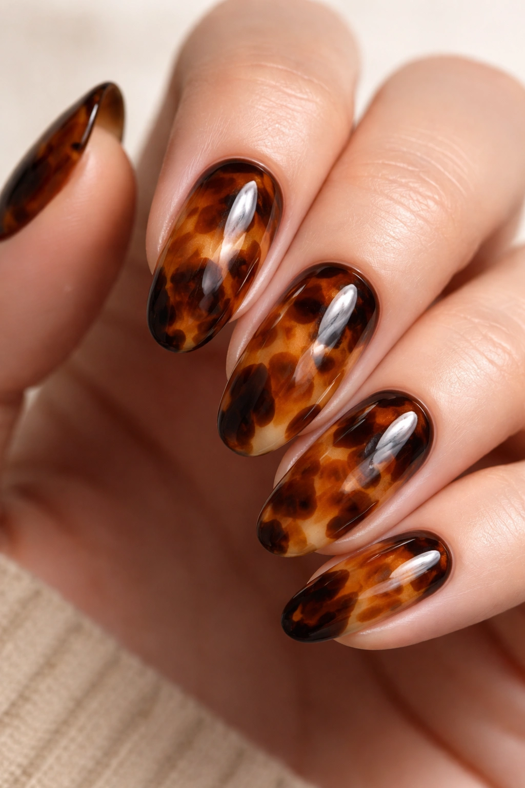 Macro shot of tortoiseshell blooming gel nail with translucent brown, amber, and cream pattern