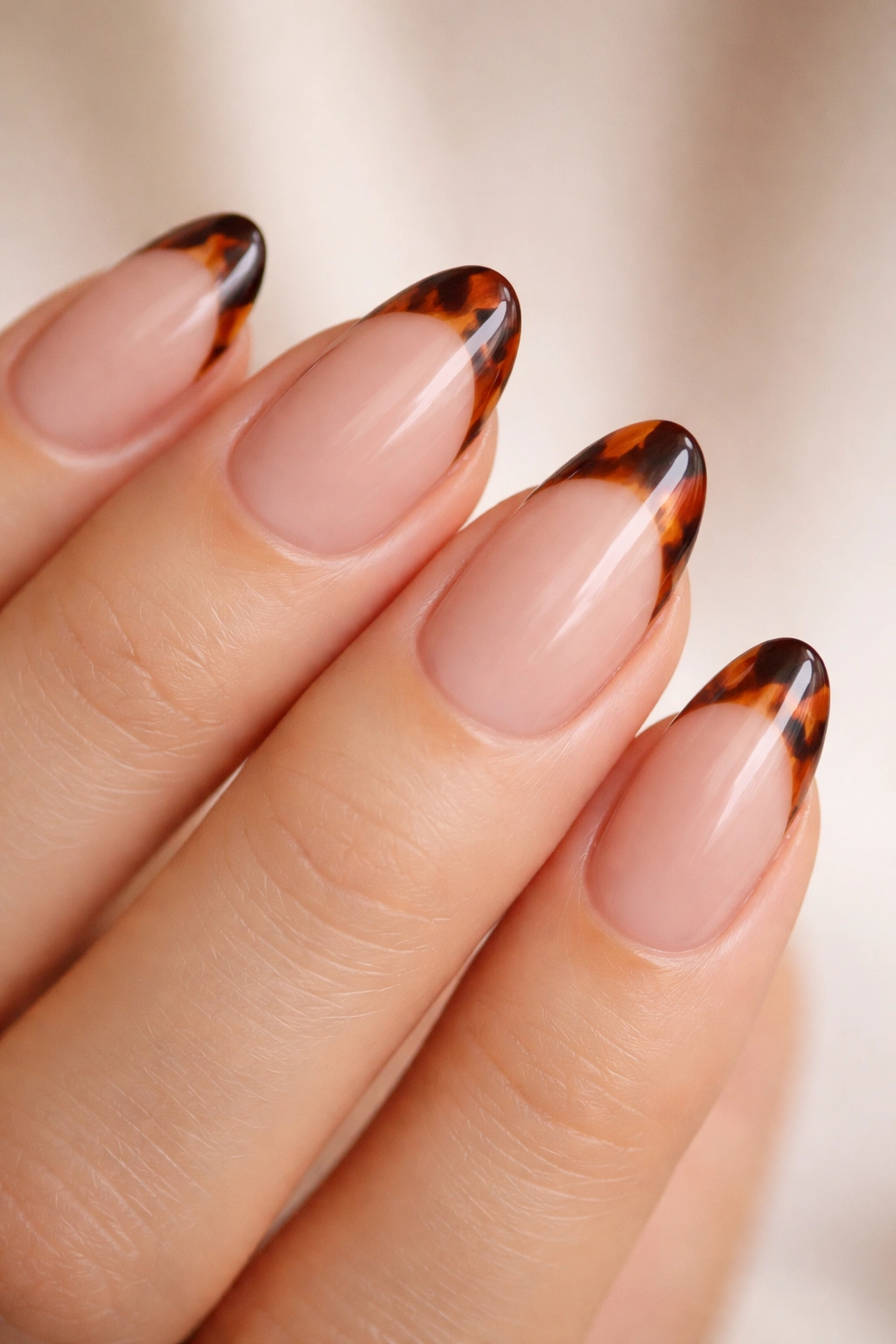 Close-up of short almond nails with tortoiseshell tips on nude base