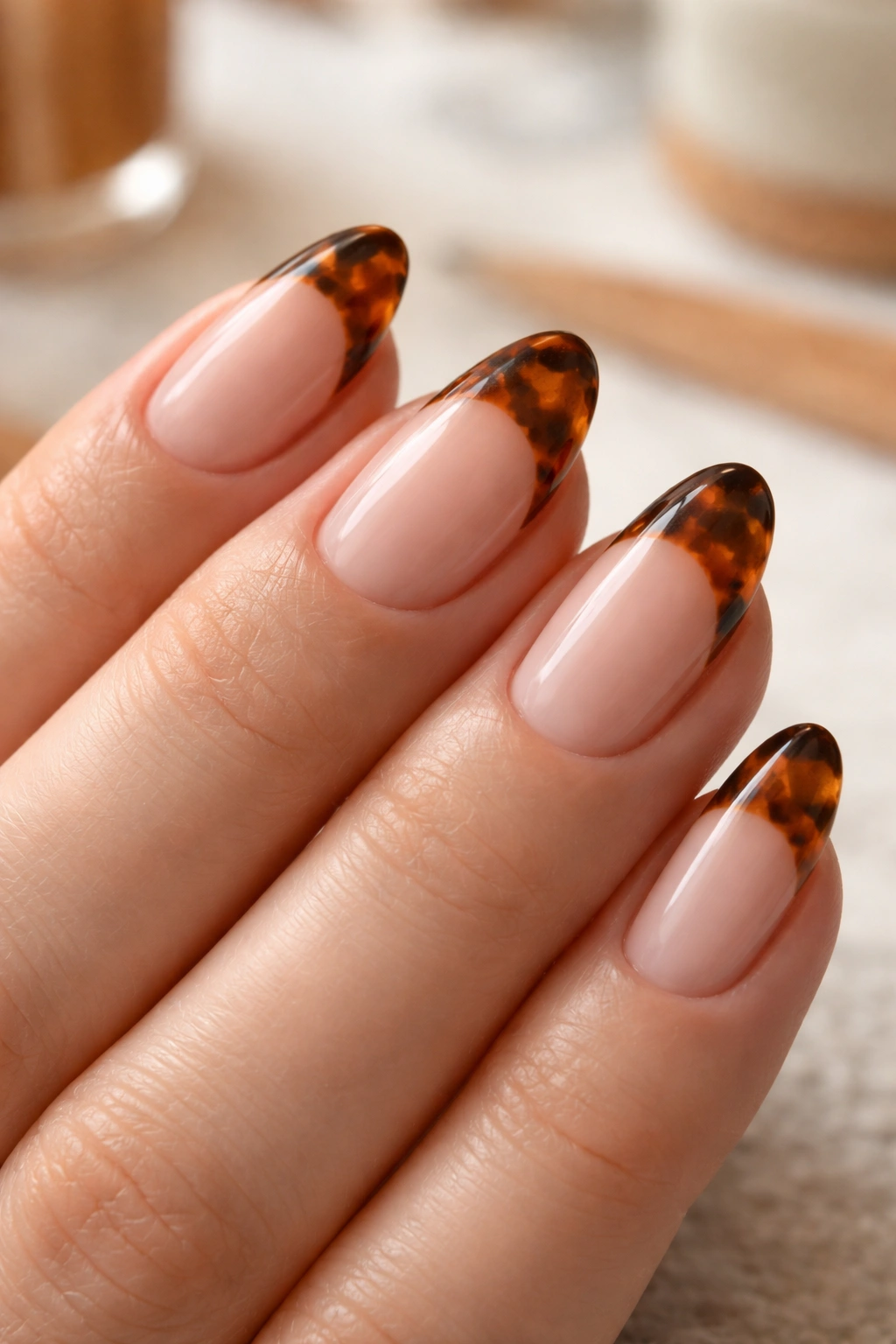 Close-up of a short almond nail with tortoiseshell brown tip in warm tones