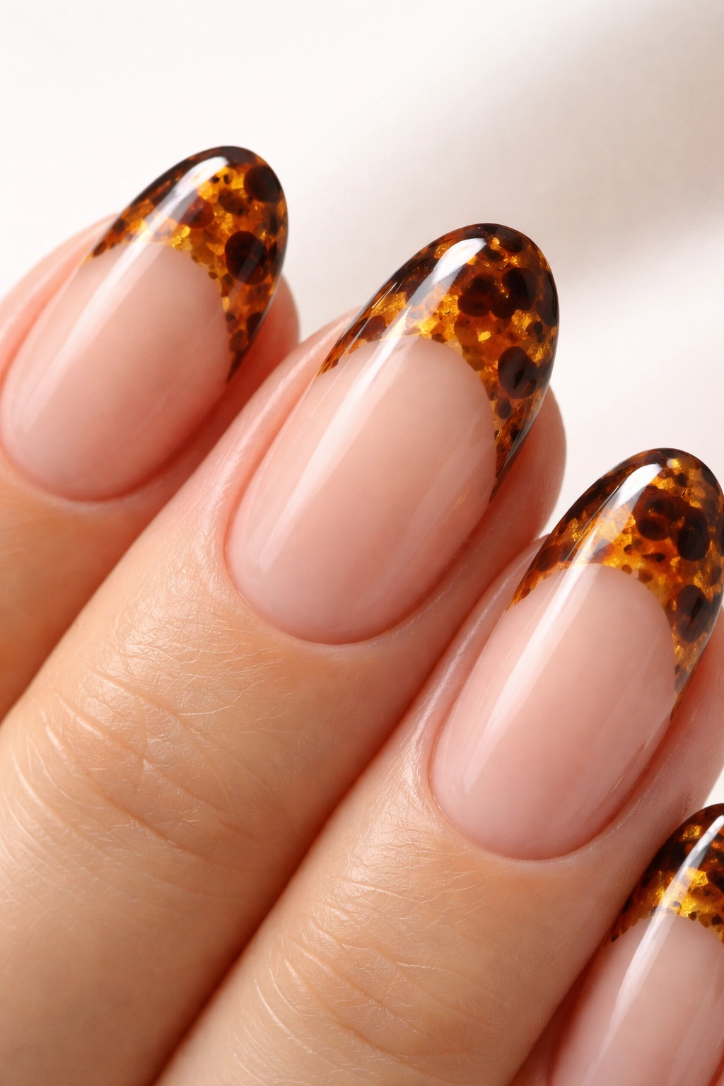 Close-up of an oval nail with tortoiseshell tip pattern in warm tones
