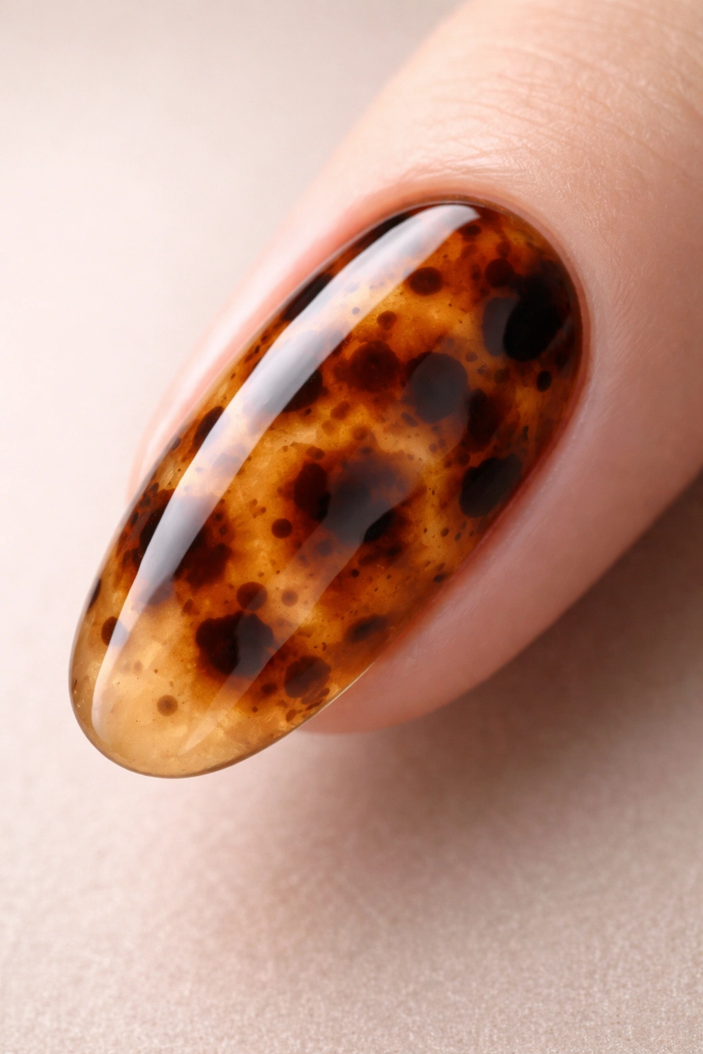 Close-up of tortoiseshell gel nails showing amber layering with brown and black spots