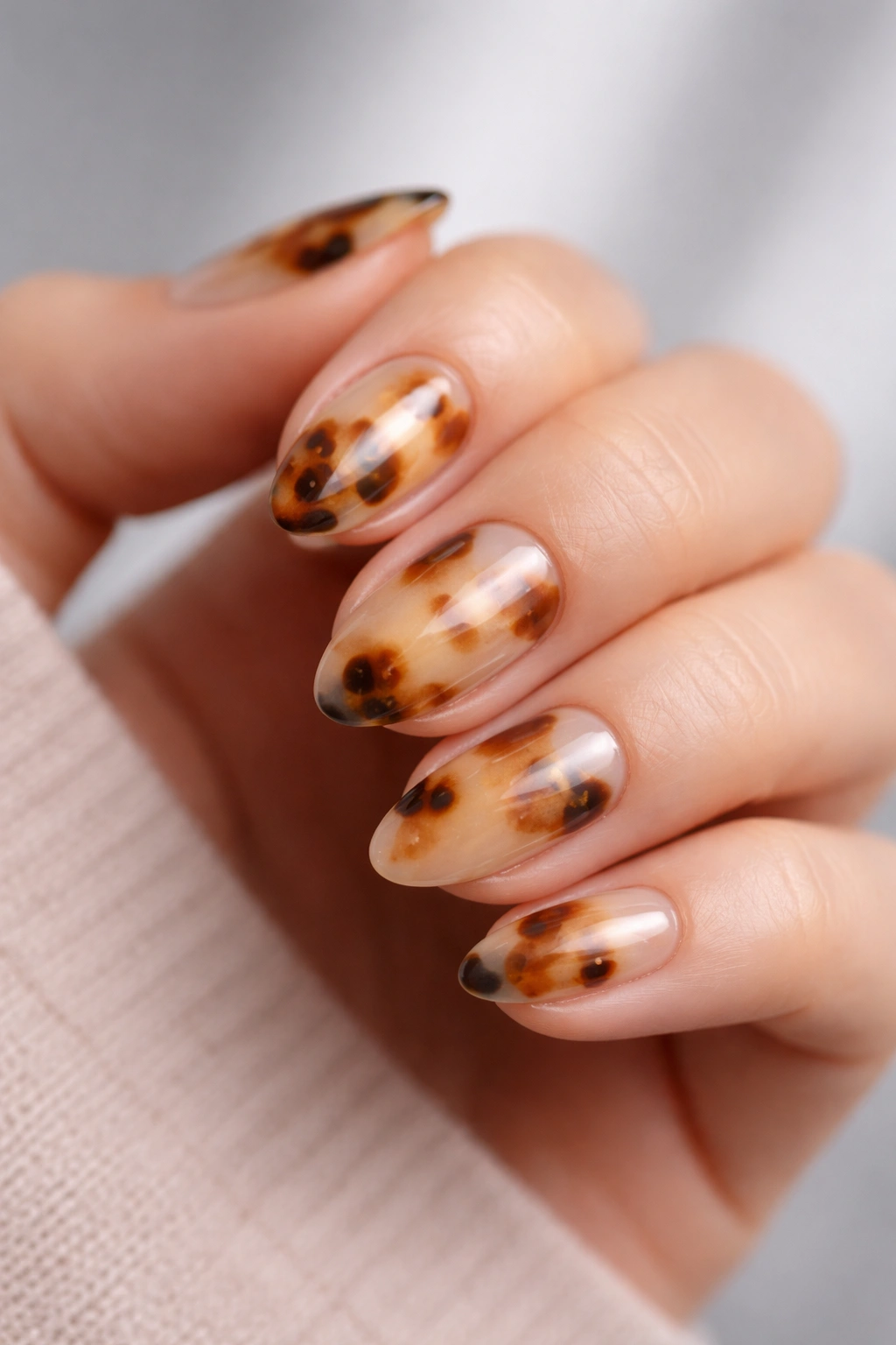 Close-up of short tortoiseshell almond nails showing airy pattern with negative space