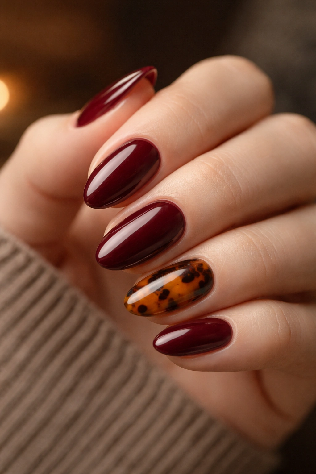 Close-up of short almond nails with tortoiseshell accent among wine red nails