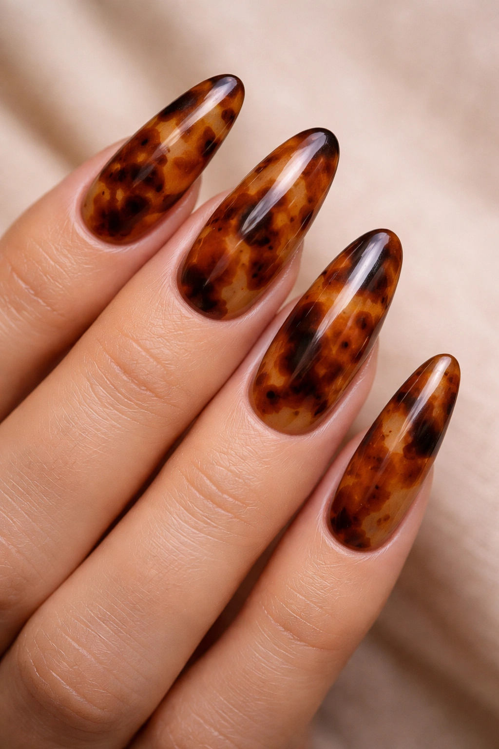 Tortoiseshell pattern on long oval nails with amber, brown, and black tones