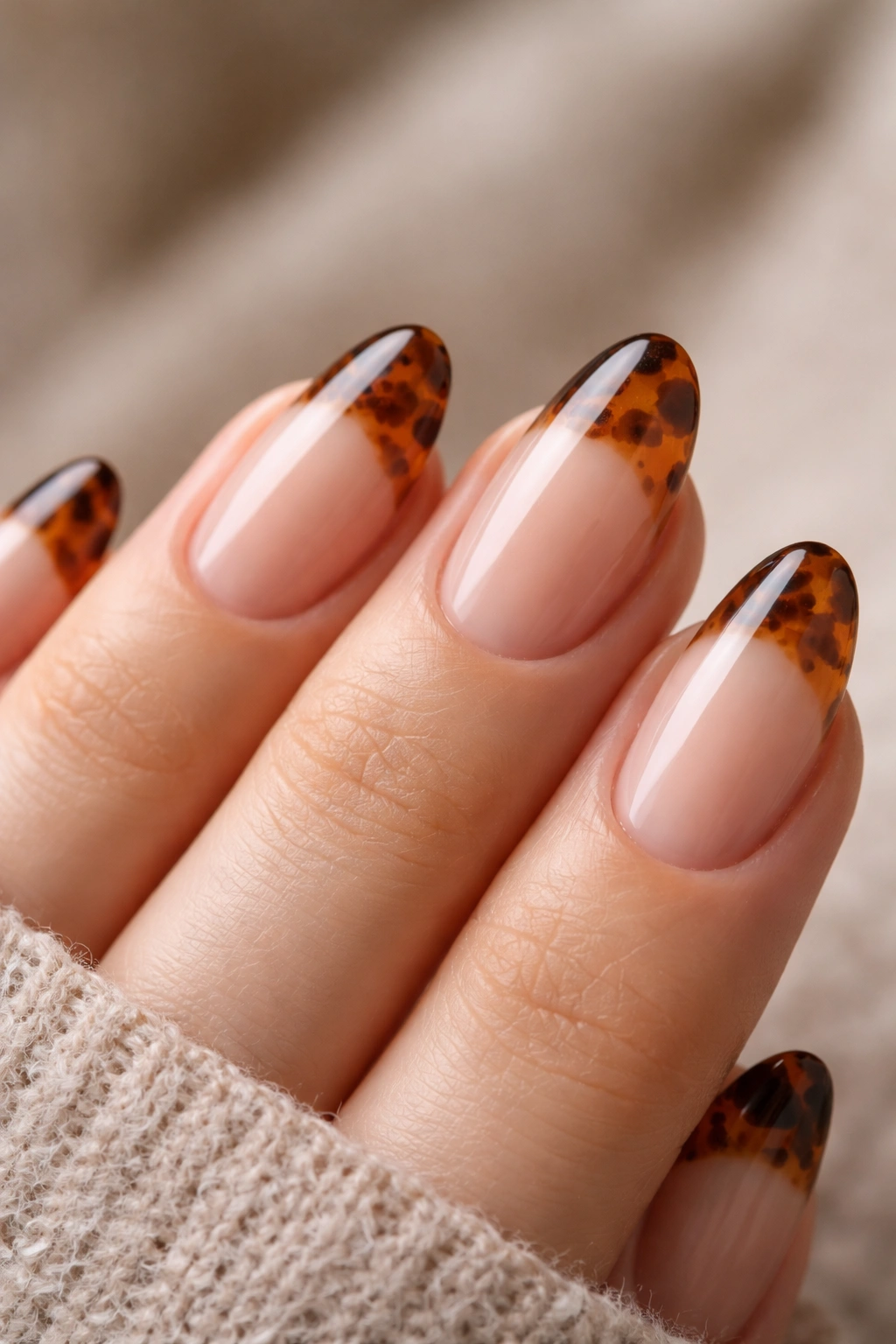 Close-up of short almond nails with tortoiseshell tip on nude base
