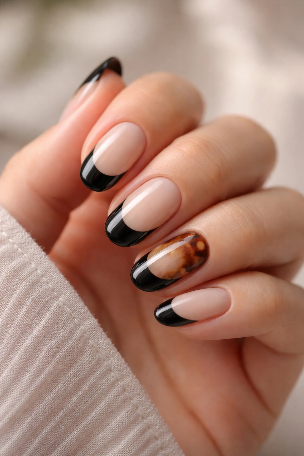 Close-up of short oval nails with tortoiseshell accents under a black edge.