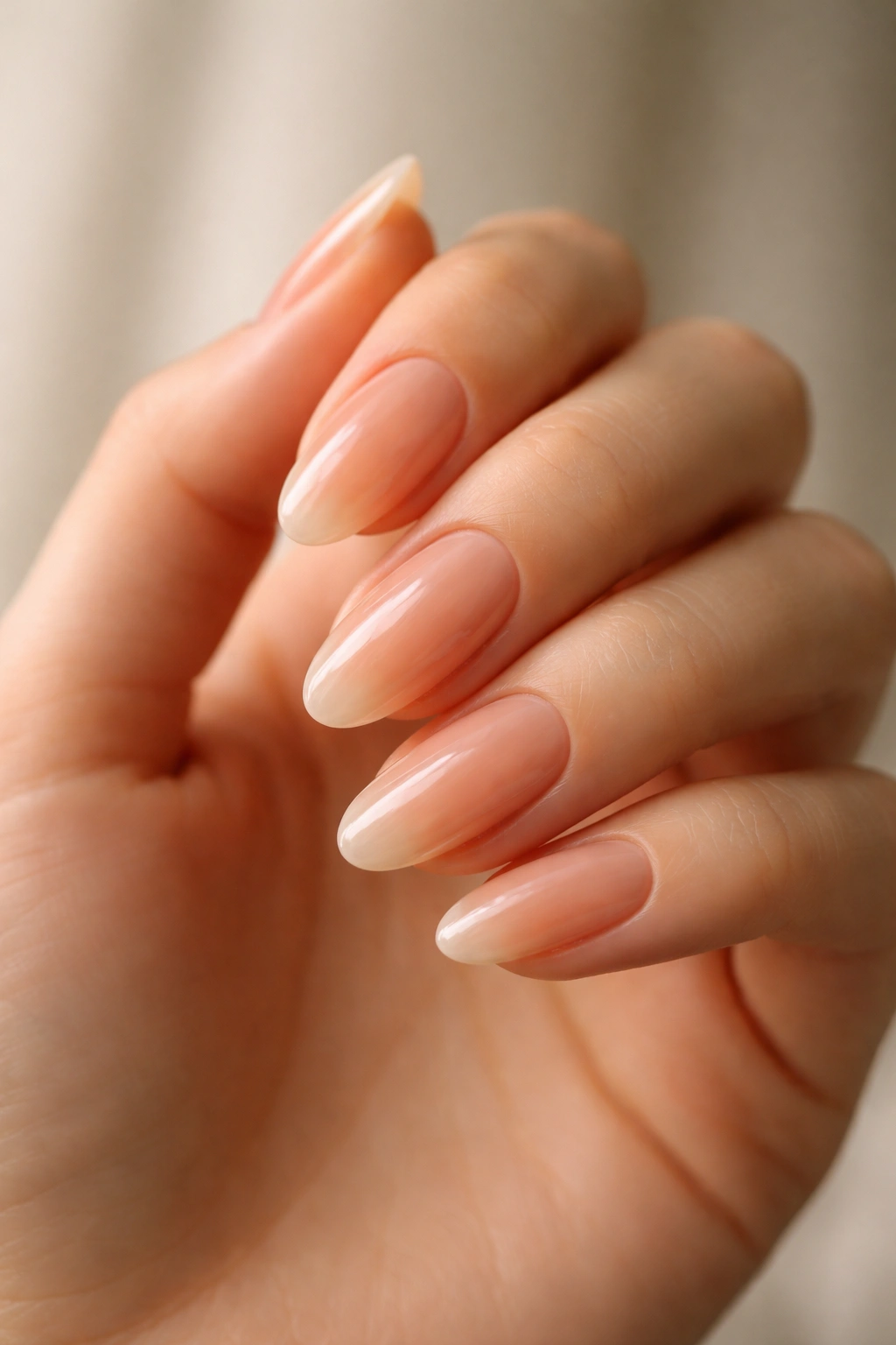 Close-up of long oval nails with translucent peach shade