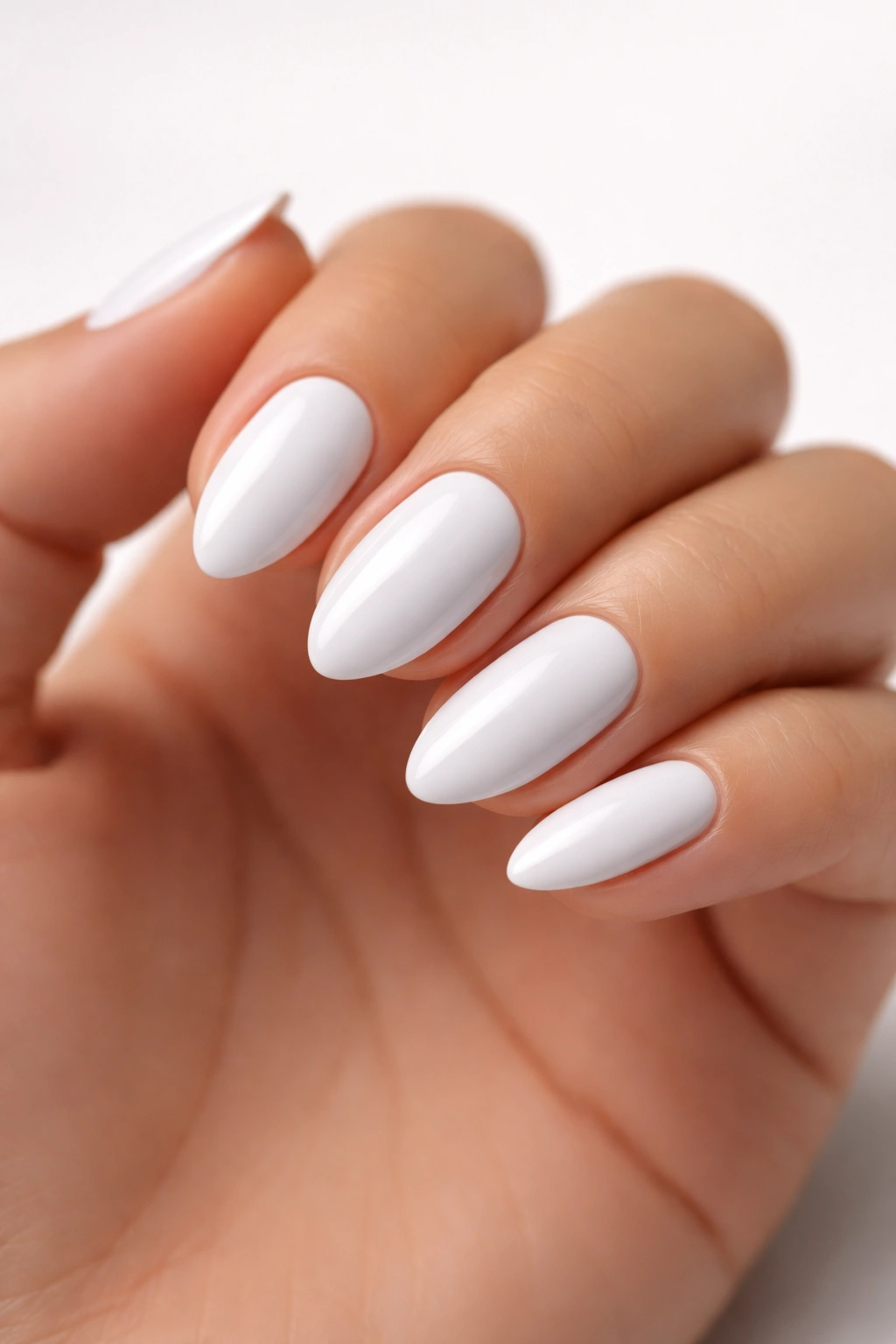 Close-up of short almond nails in true white glossy polish