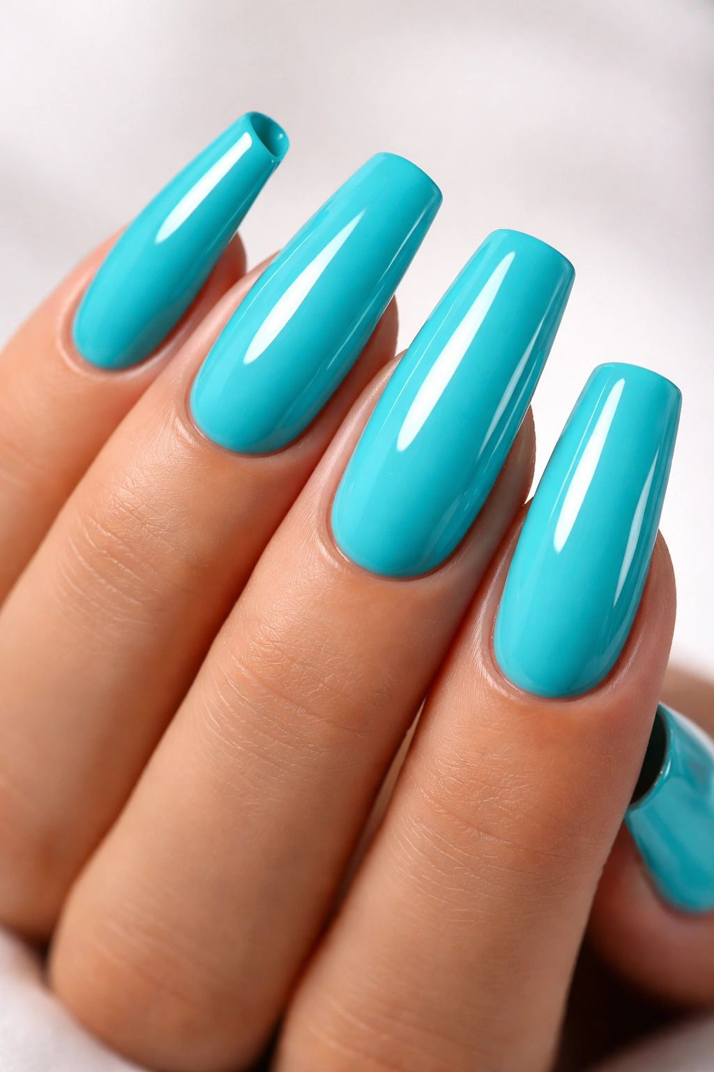 Close-up of turquoise blue acrylic nails on a hand with glossy finish against a neutral background