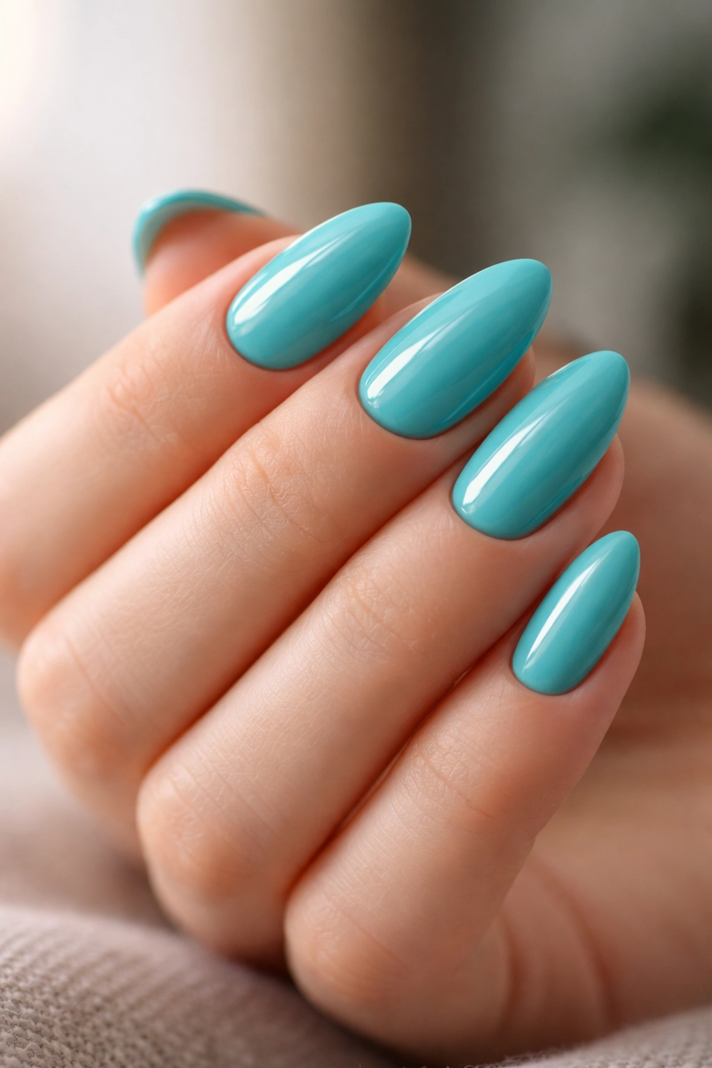 Hand with glossy turquoise short almond nails