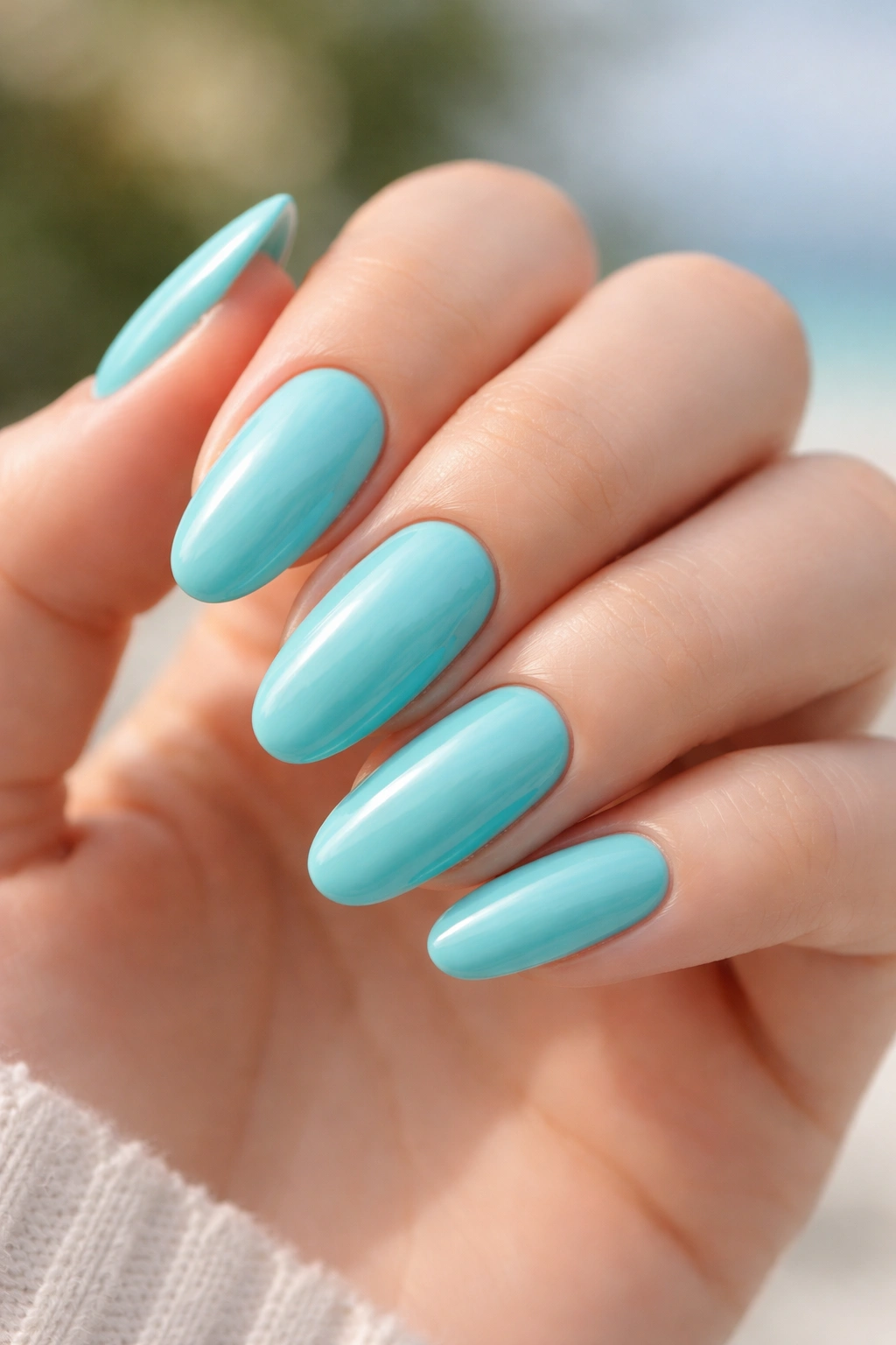 Close-up of long oval nails painted turquoise cream finish