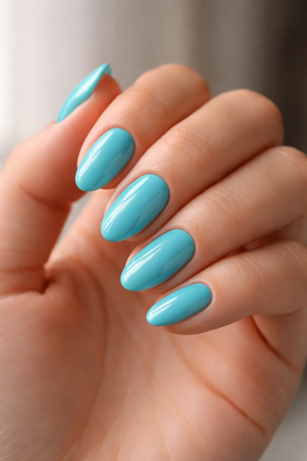 Hand with short almond turquoise nails