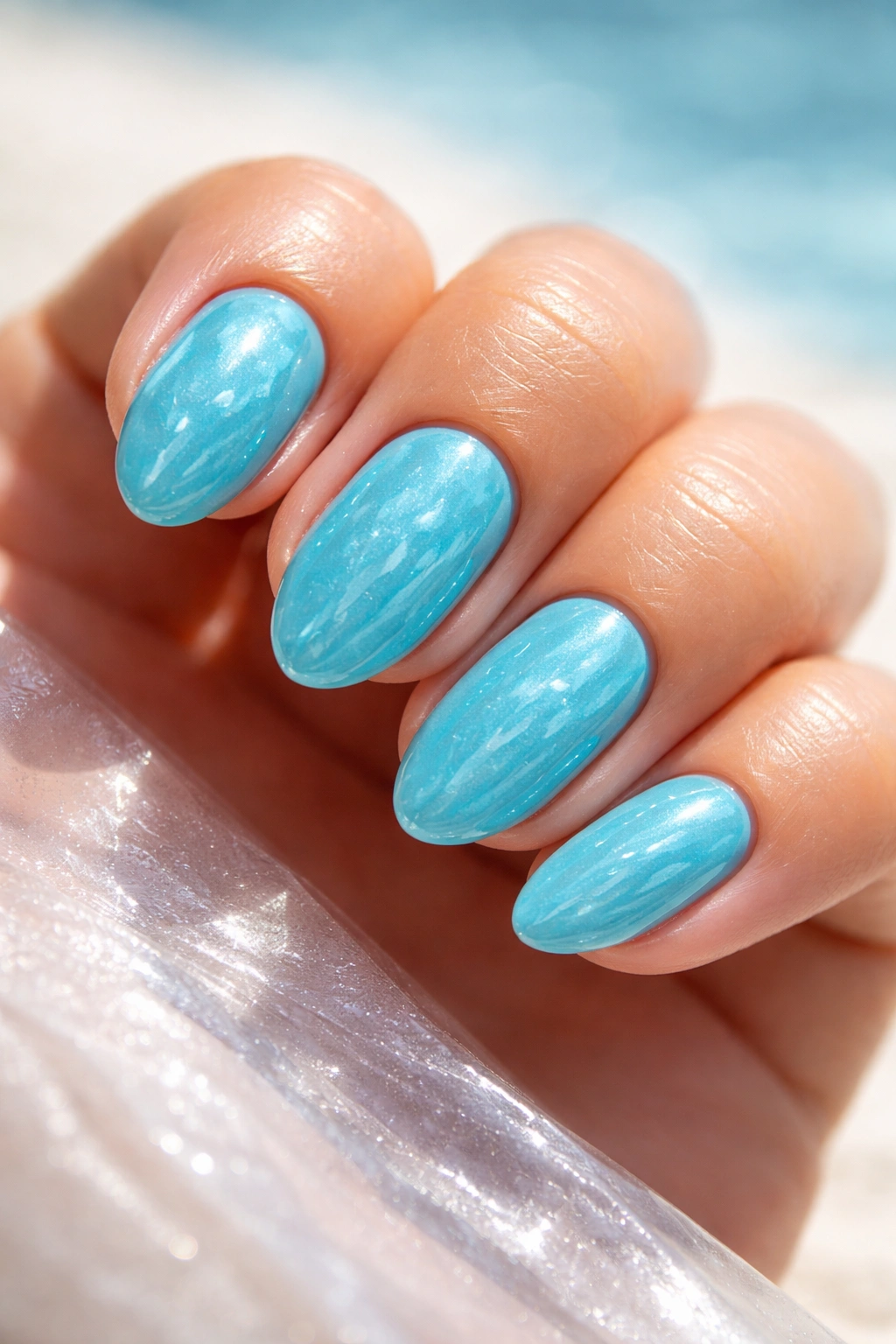 Close-up of turquoise short almond nails with a glossy pool-water look