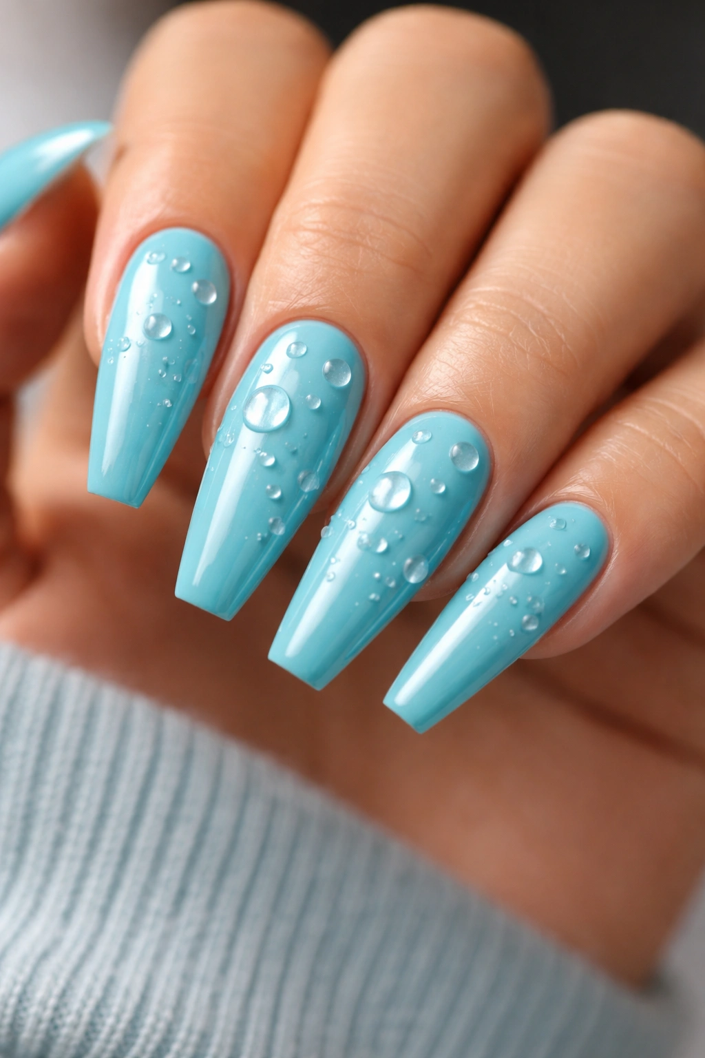 Close up of turquoise nails with glossy water droplets on ballerina shape
