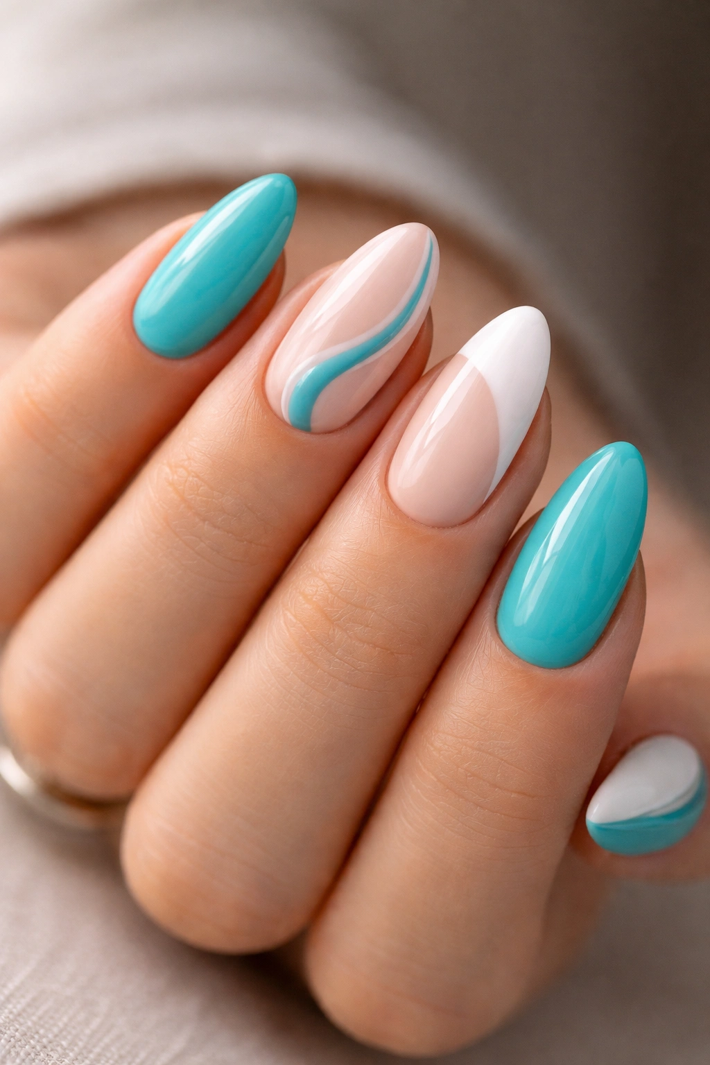 Short almond nails with turquoise, nude, and white accents