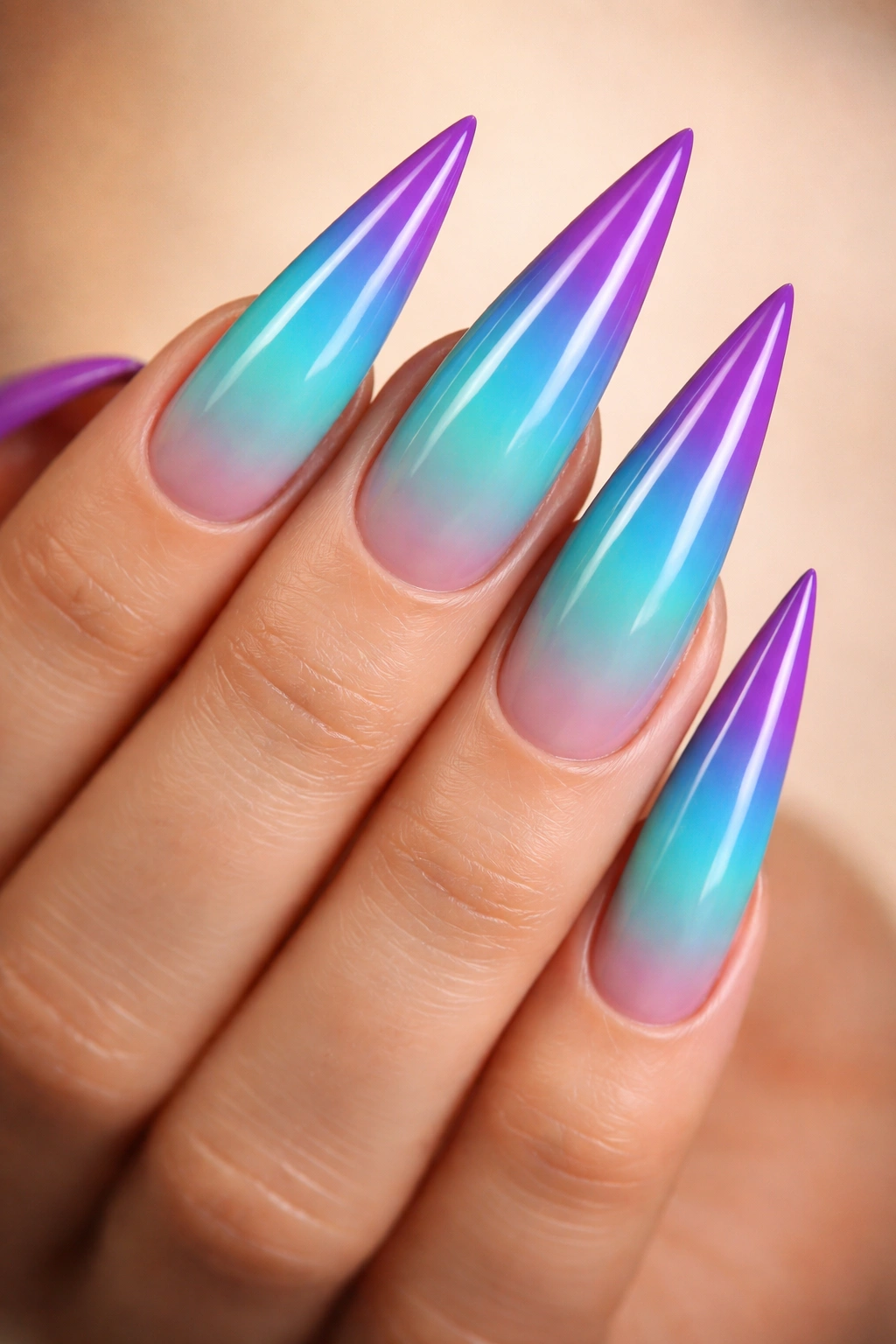 Close-up of turquoise to purple ombre stiletto nails with sunset gradient