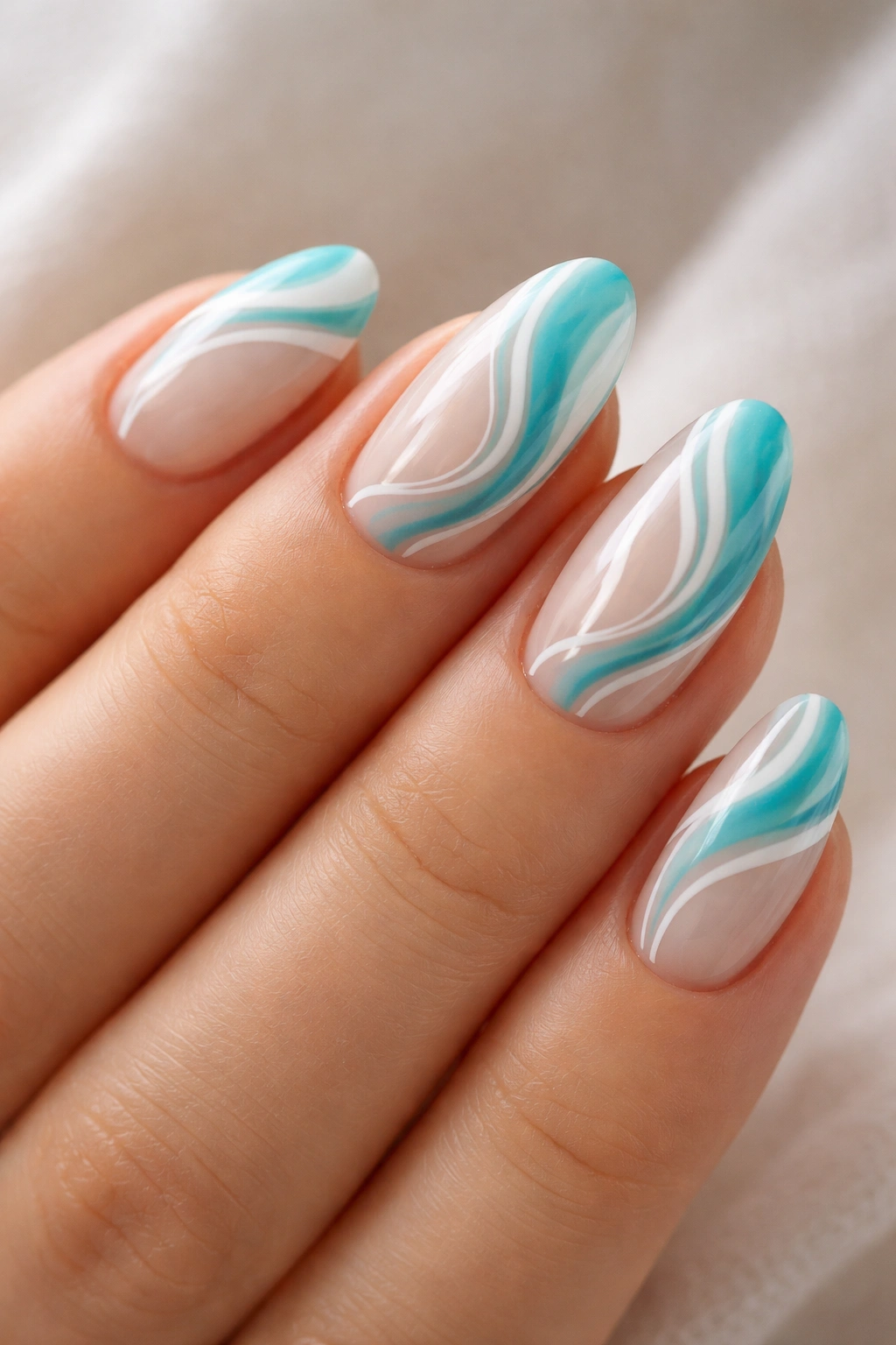 Close-up of short almond nails with turquoise and white swirl designs