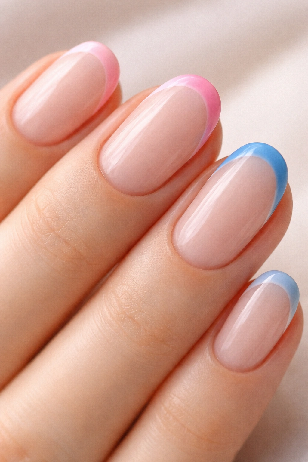 Close-up of short oval nails with two-tone tips in two colors