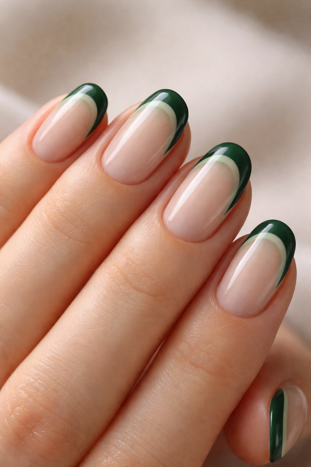 Close-up of two-tone green French tips on short oval nails