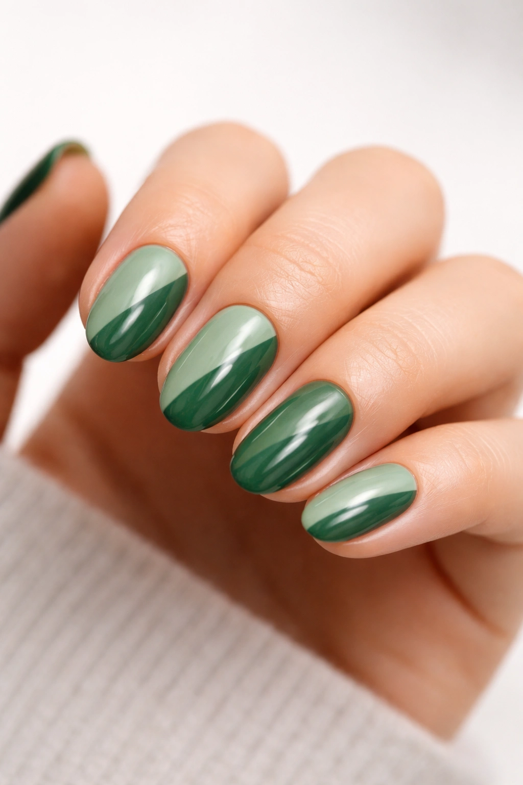 Close-up of two-tone short almond nails with a diagonal green split