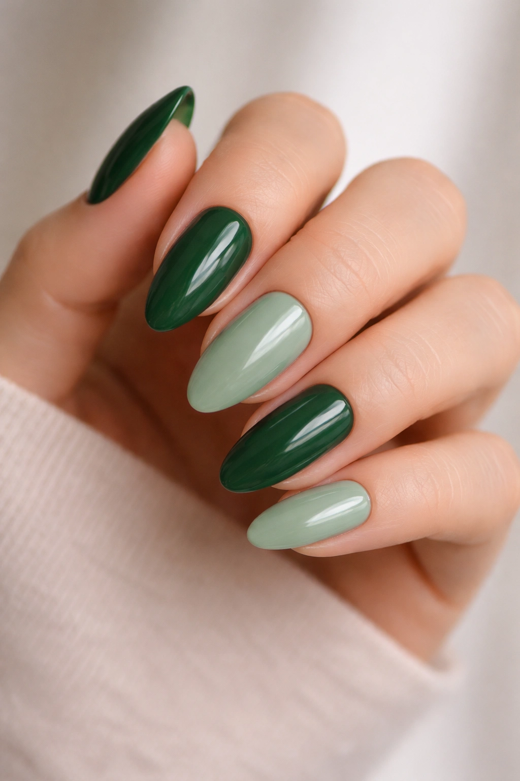 Almond nails alternating deep green and sage.