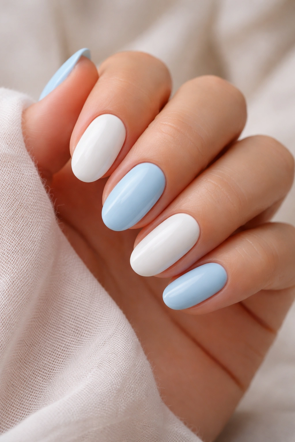 Close-up of two-tone baby Blue and milky white nails on short almond nails
