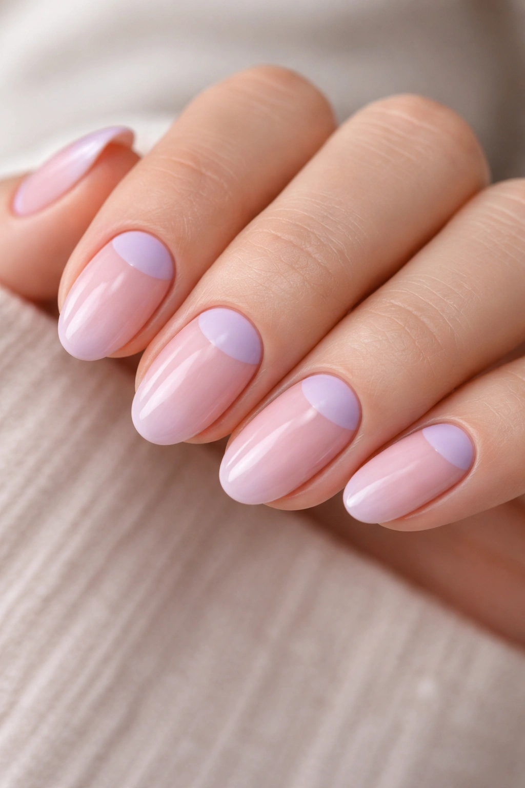 Close-up of two-tone pink and lilac half-moon nails on a short almond nail