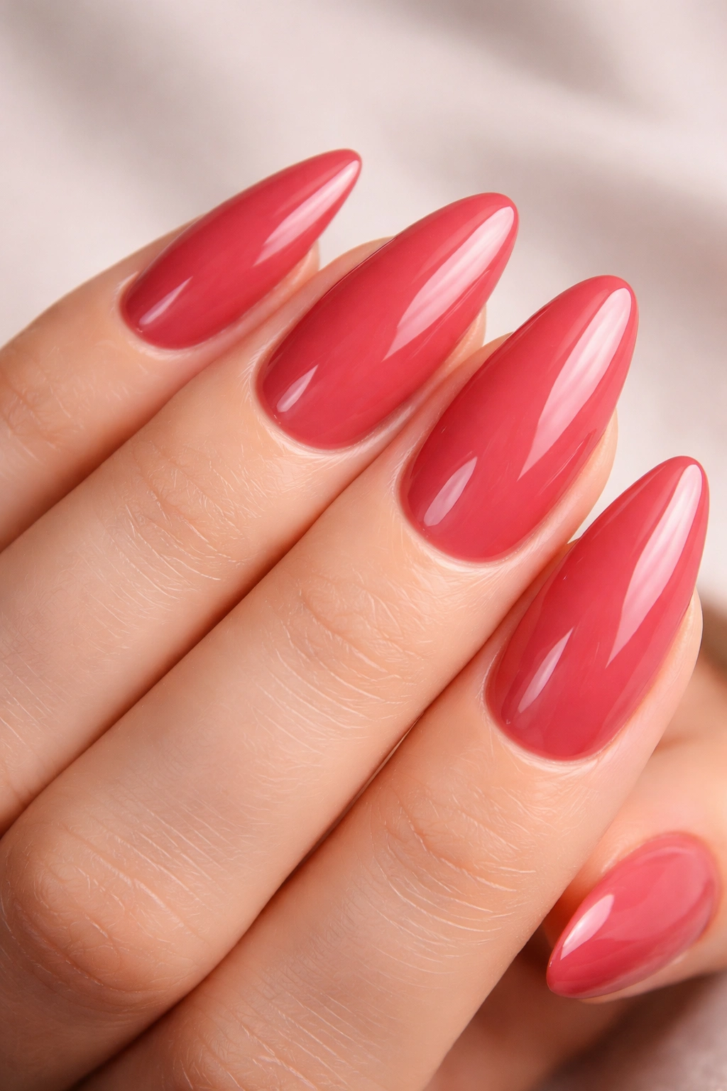 Close-up of Valentine's nails with glossy pink-red polish and pristine cuticles.