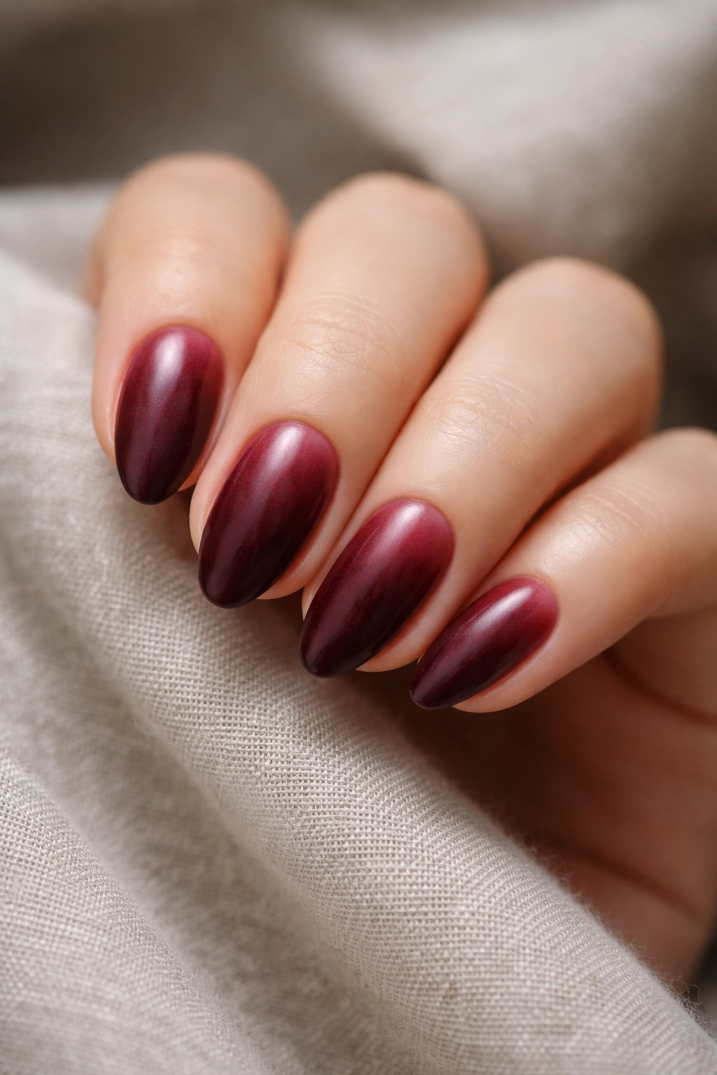 Close-up of short almond nails with velvet burgundy airbrush finish