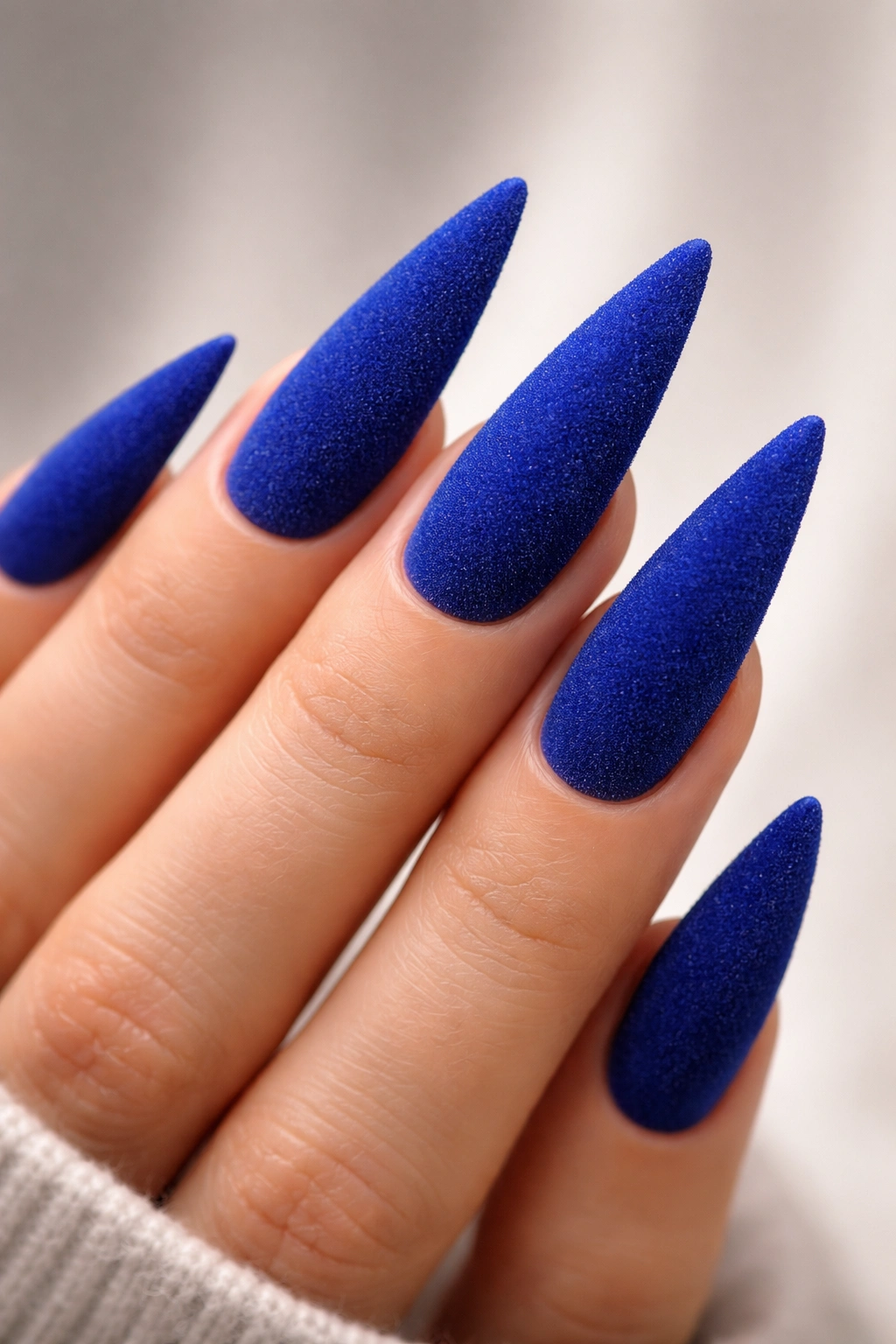 Macro shot of velvet royal blue stiletto nails with fuzzy texture