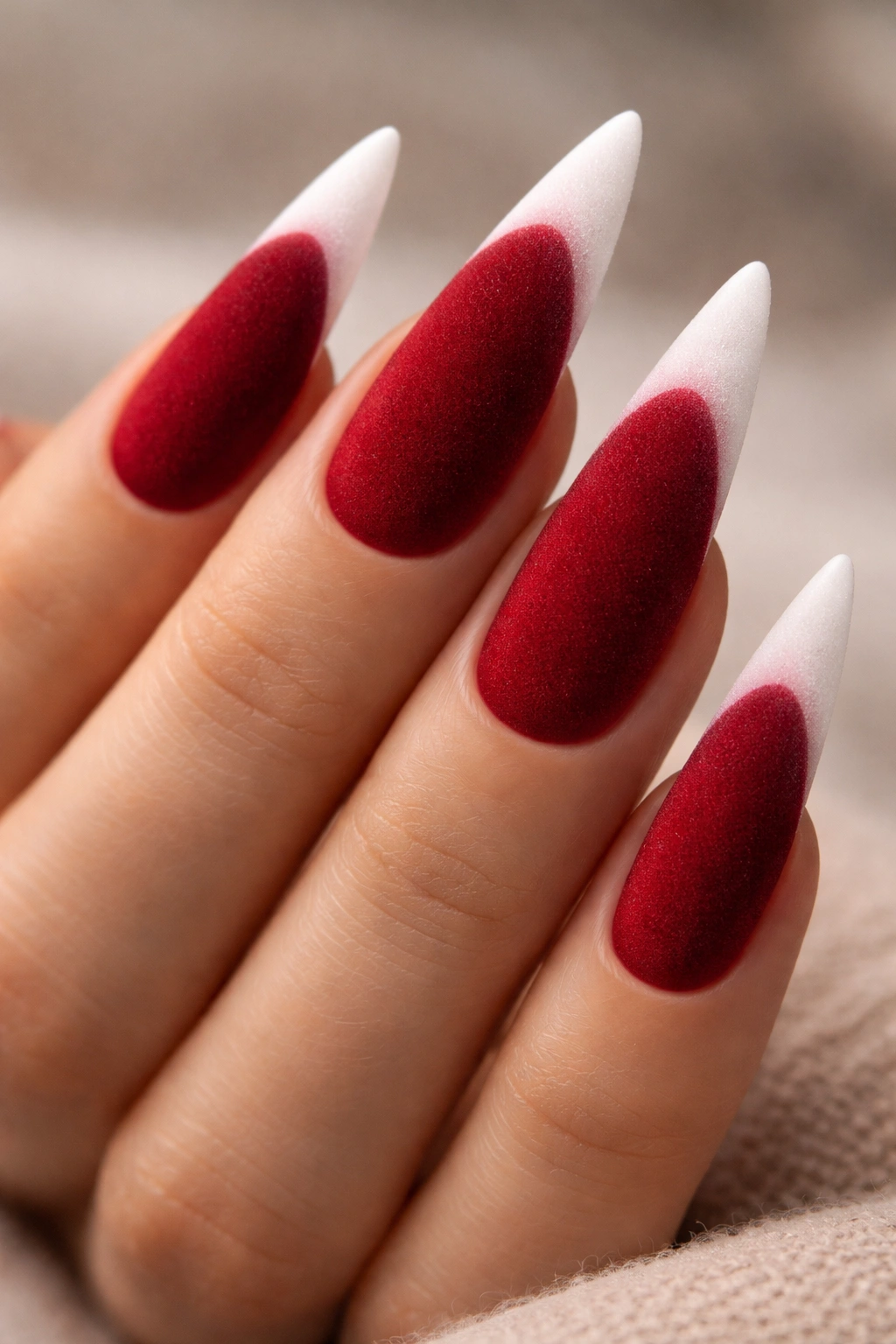 Close-up velvet-textured red nails with white tips