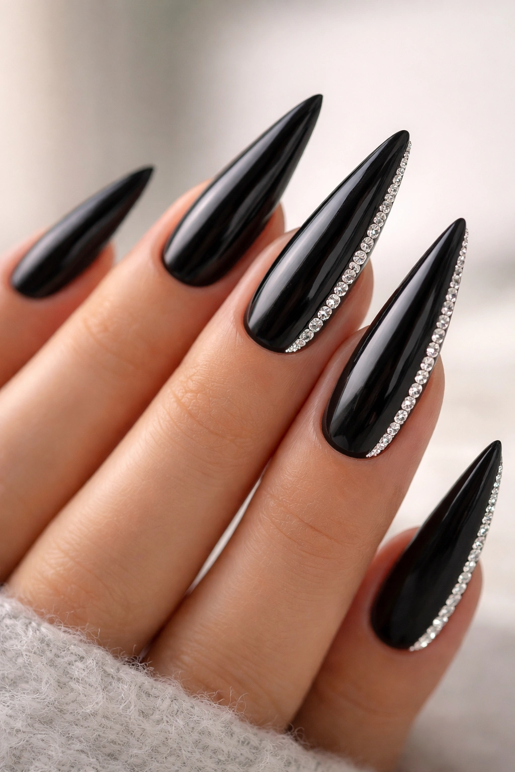 Stiletto nails with a vertical rhinestone stripe along the outer edge