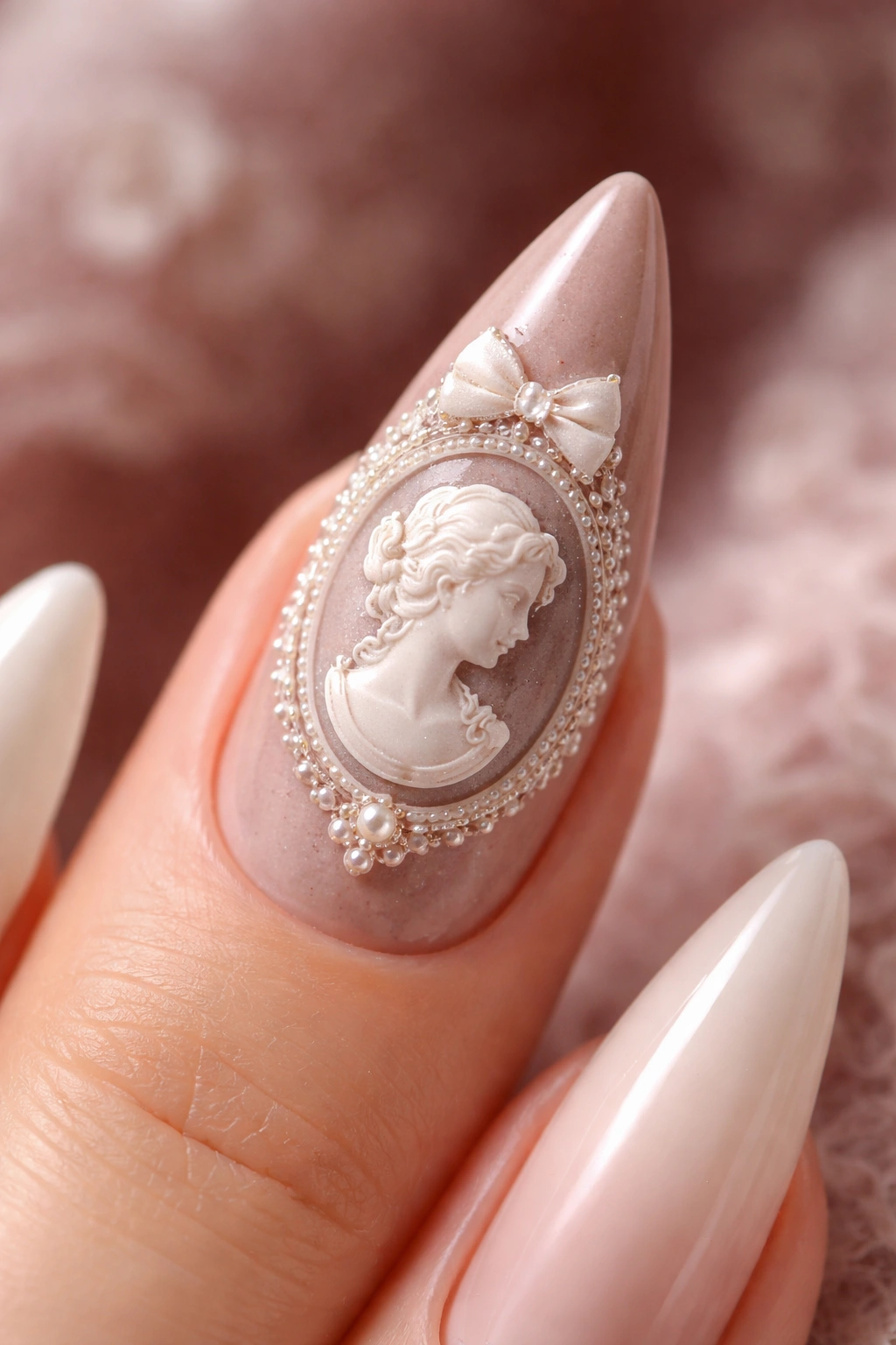 Close-up of a stiletto nail featuring a white cameo silhouette on a dusty backdrop