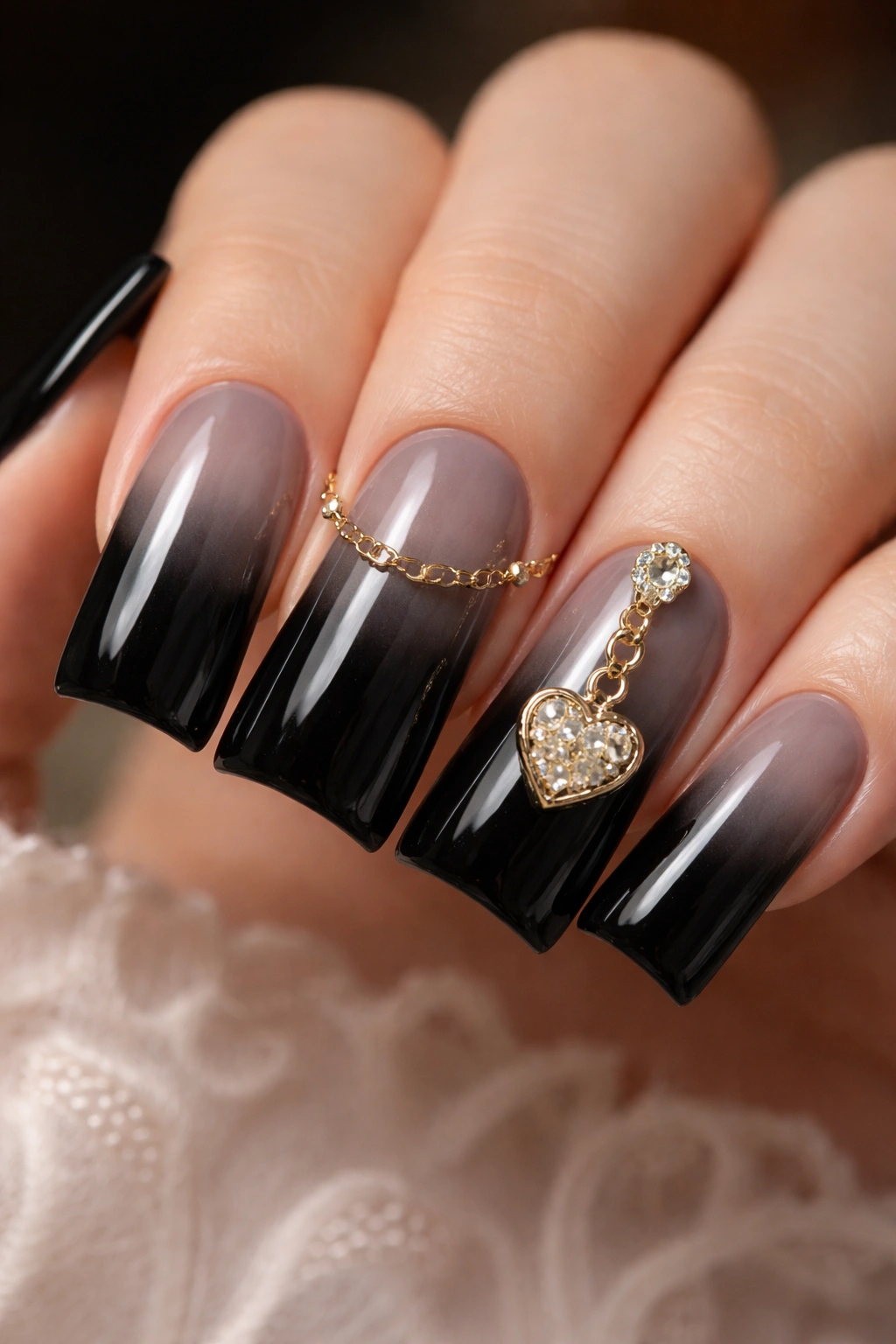 Close-up of black duck nails with a delicate vintage chain and small pendant