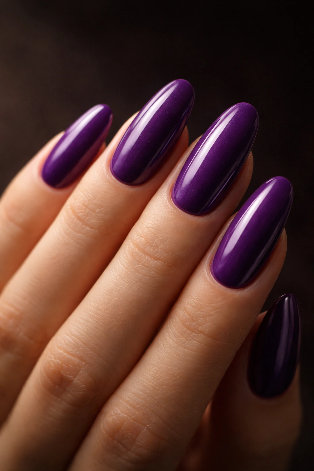Close-up of long oval nails painted violet purple with velvet-like depth