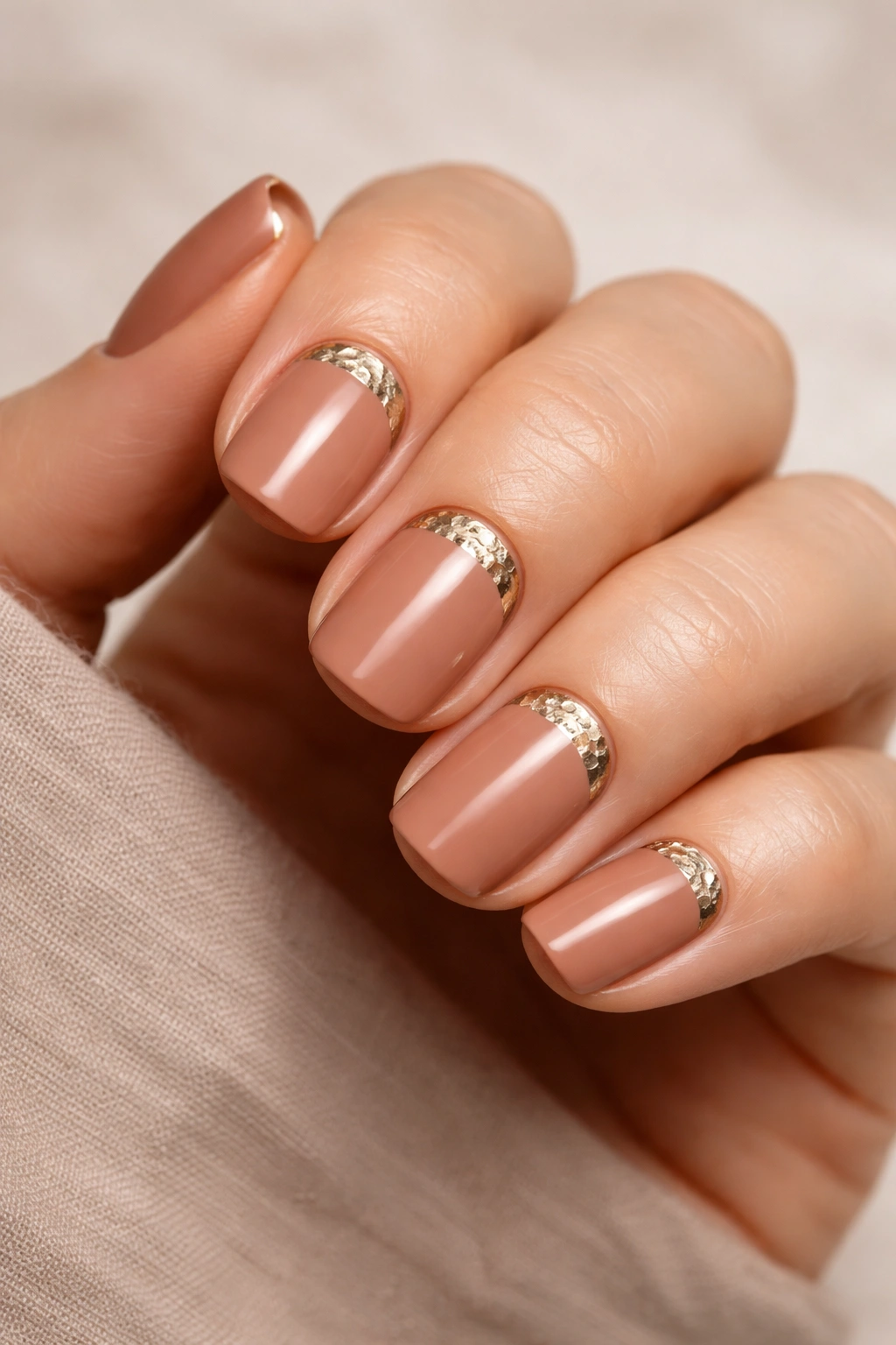Close-up of warm clay nails with hammered metallic accents on short squoval nails