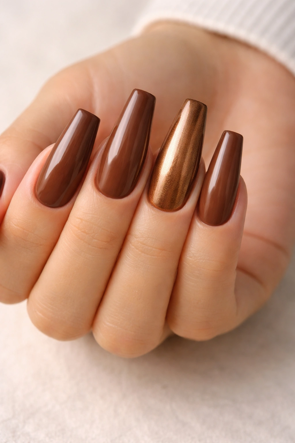 Close-up of coffin nails in warm cocoa brown with bronze metallic accent nail.