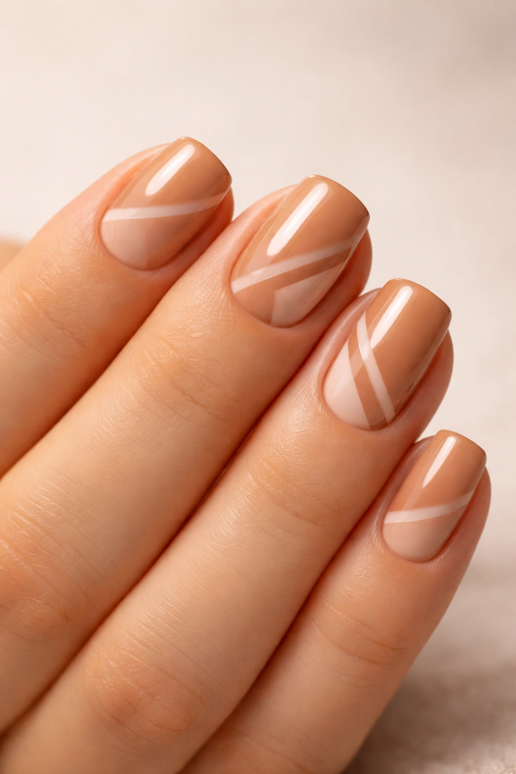 Warm tan nails with negative-space geometric design on short squoval nails