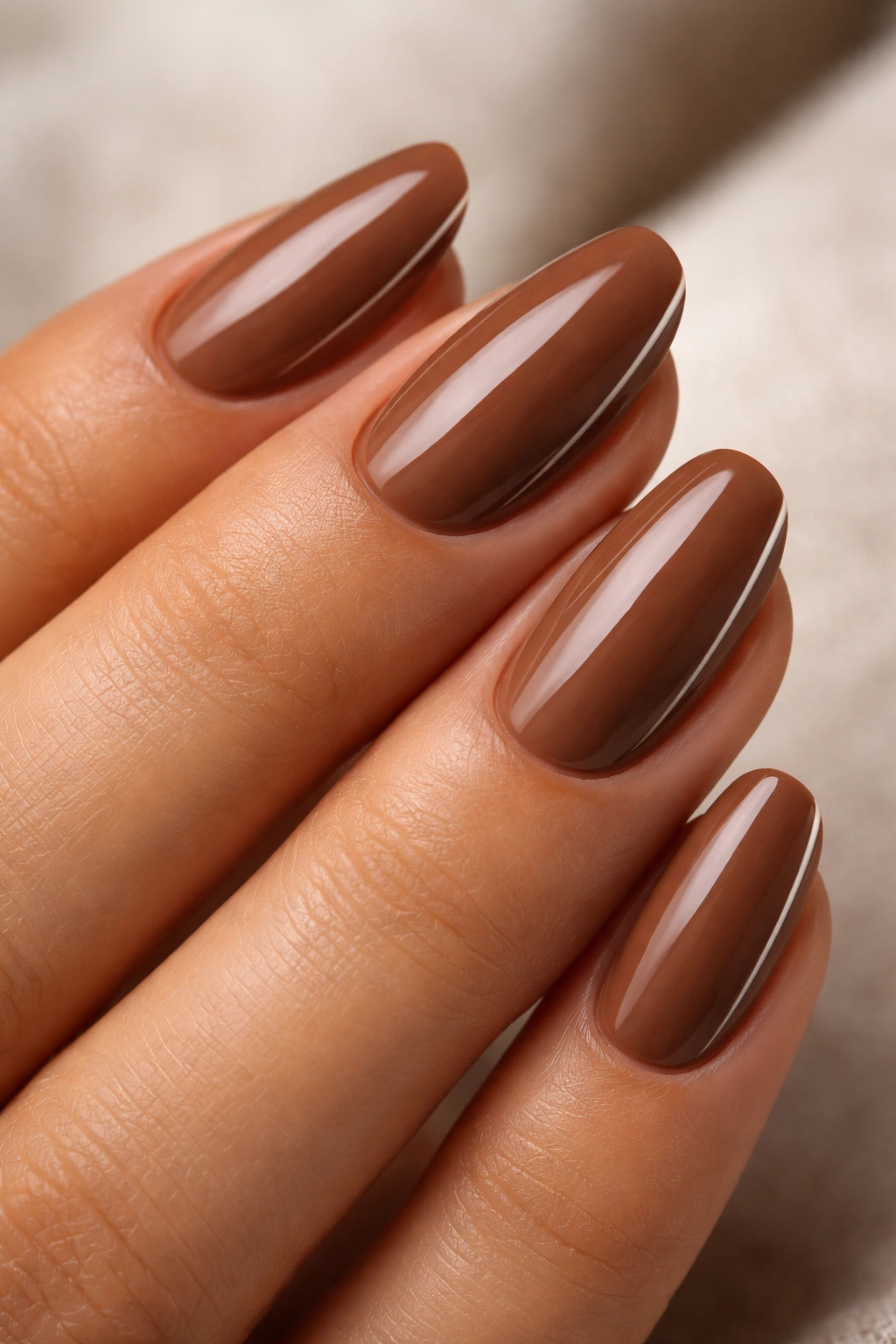 Short almond nails in warm walnut brown with a thin minimal edge