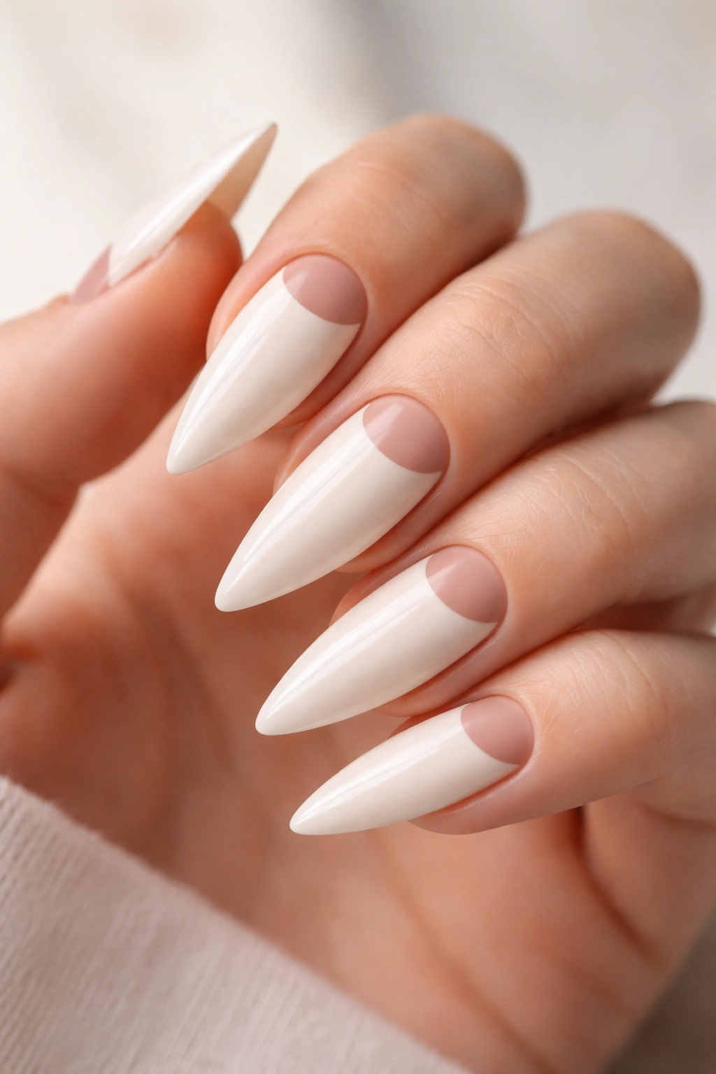 Close-up of warm white stiletto nails with negative space half-moon near cuticle