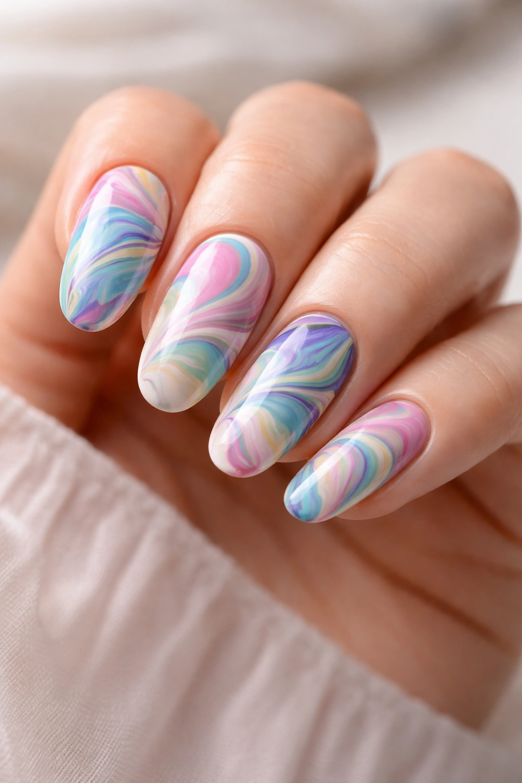 Close-up of water marble nails with swirling patterns in a neutral studio setting
