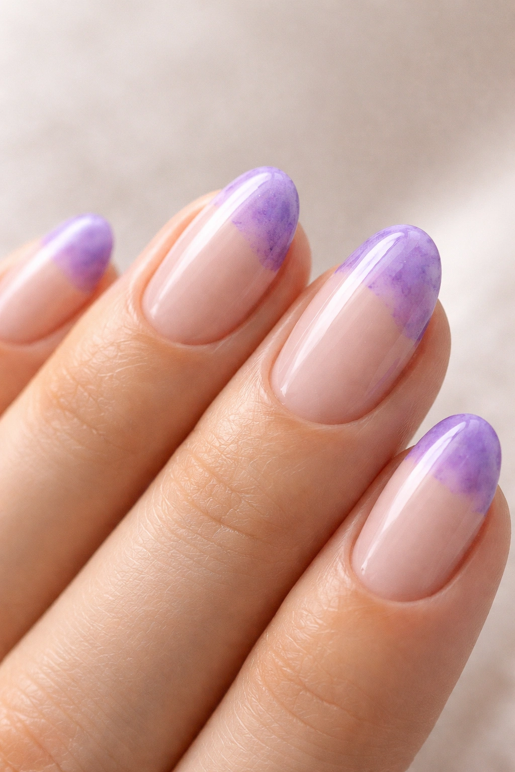 Close-up of a short almond nail with watercolor-wash purple French tip showing translucent, painterly edge