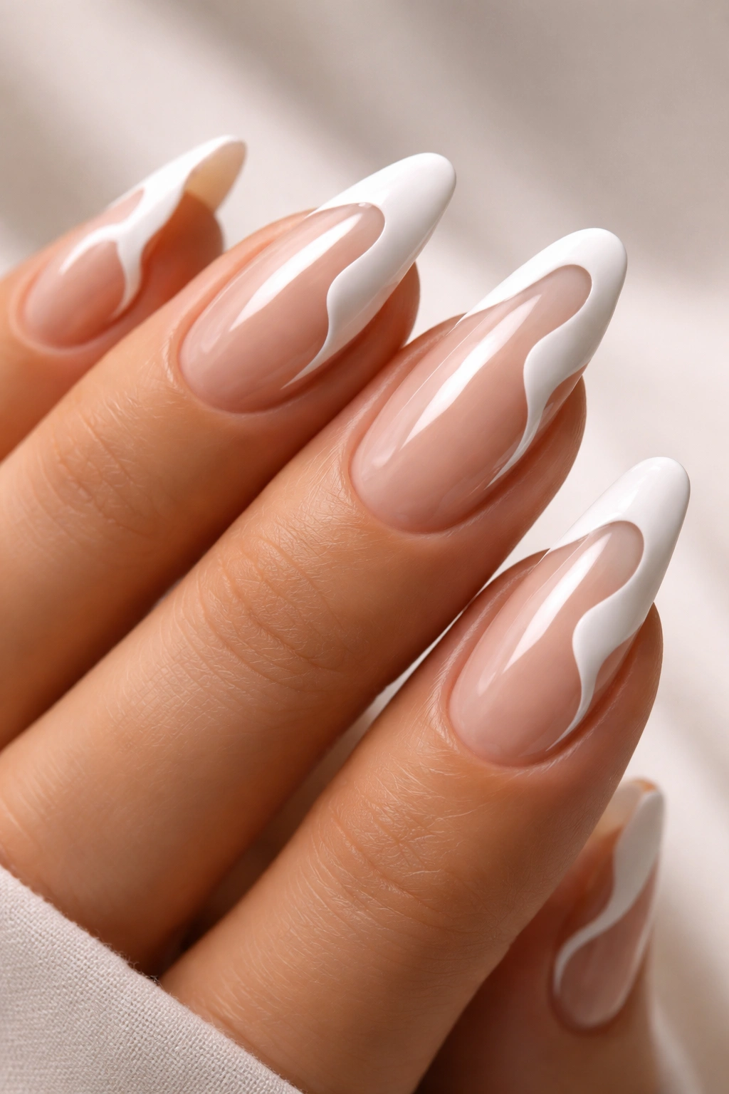 Close-up of hand with wavy French tips on nude nails, glossy finish