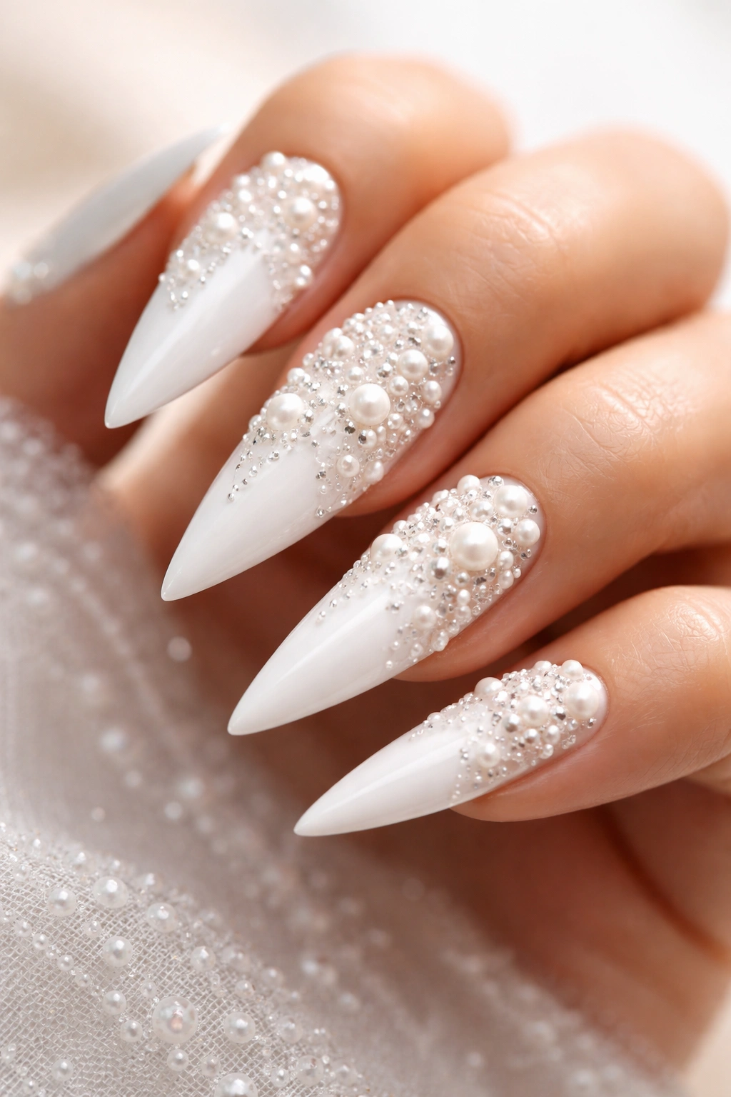 Close-up of white stiletto nails with 3D pearl and bead accents