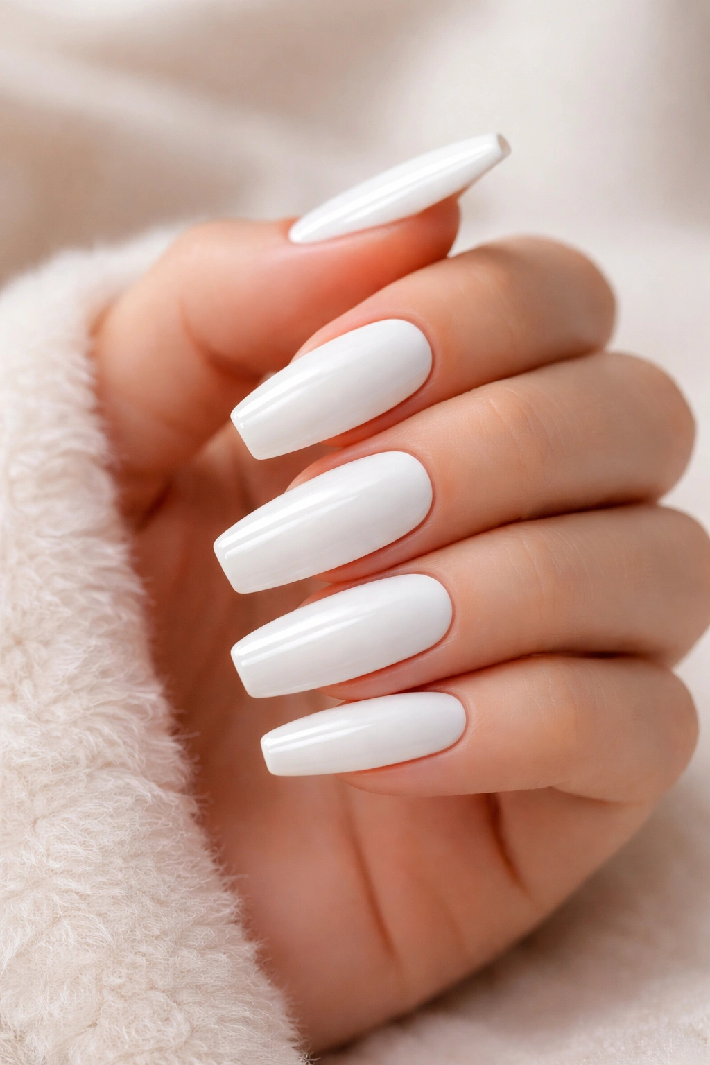 Close-up of white acrylic nails on a hand with a neutral background.