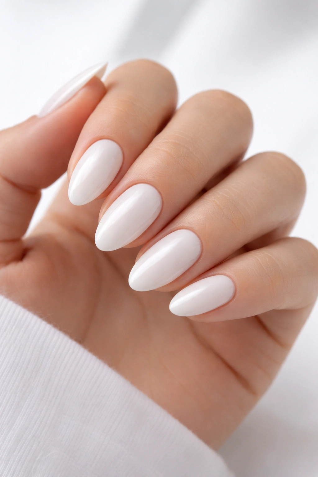 Close-up of clean white almond nails on a white background.