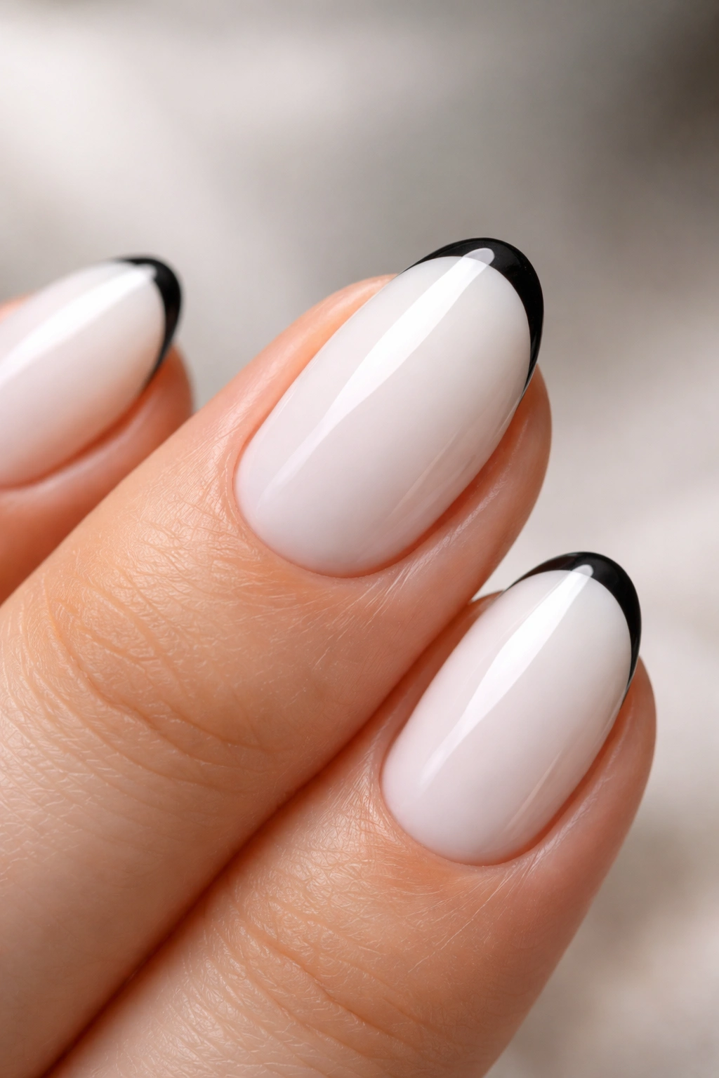 Close-up of a short white almond nail with a black micro-French tip on a glossy finish