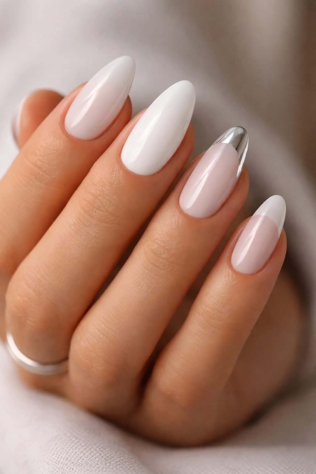 Close-up of a hand showing multiple white almond nail looks without text.