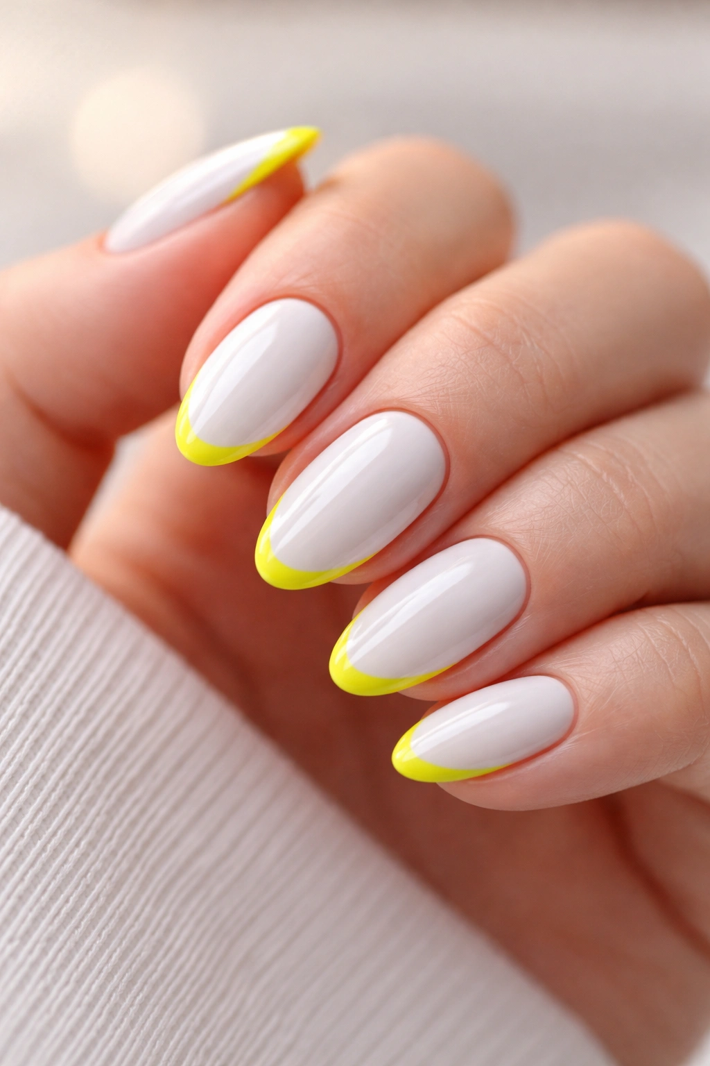 Close-up of short white almond nails with neon yellow edges